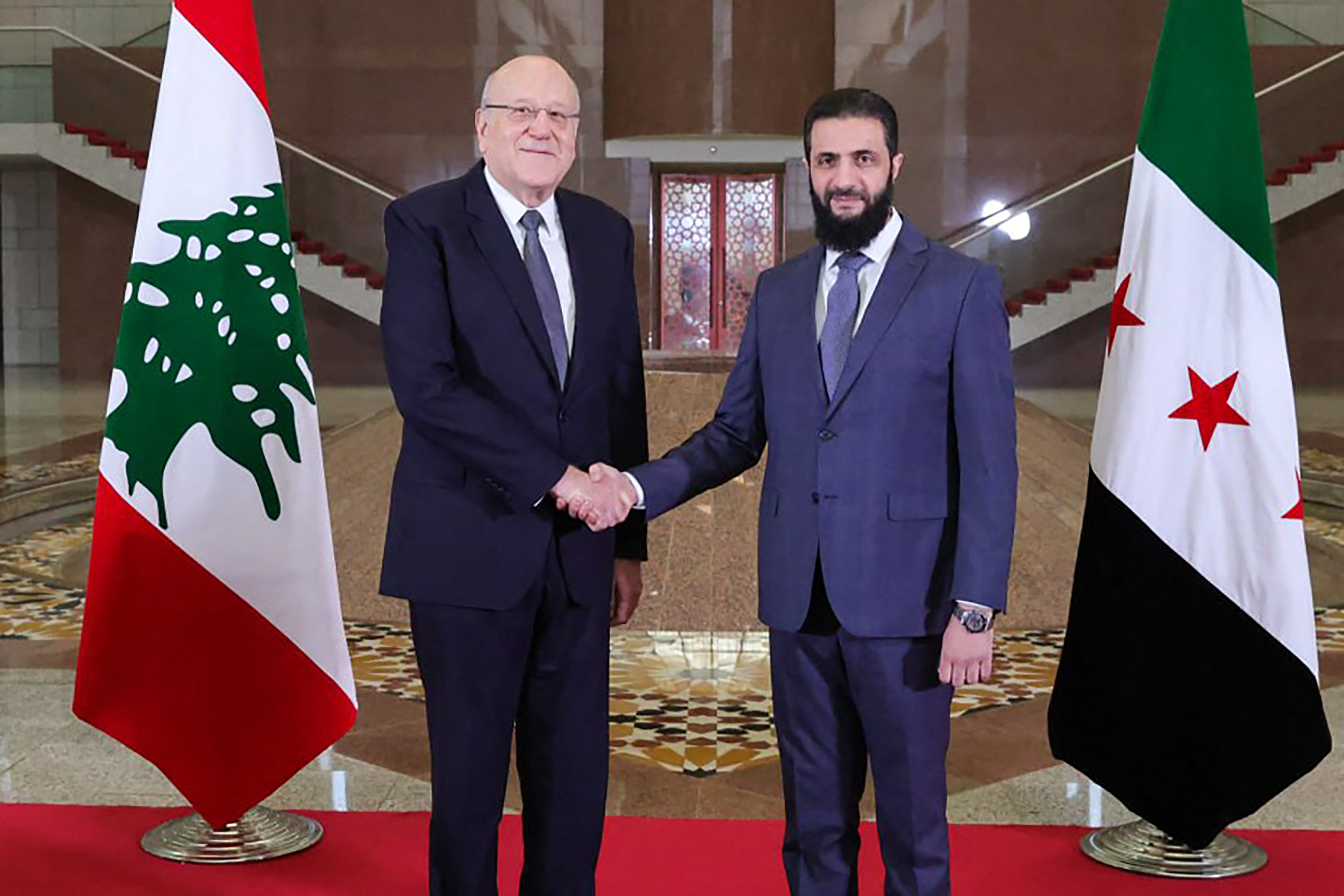 Lebanon's Prime Minister Najib Mikati shakes hands with Syria's new leader Ahmed al-Sharaa.