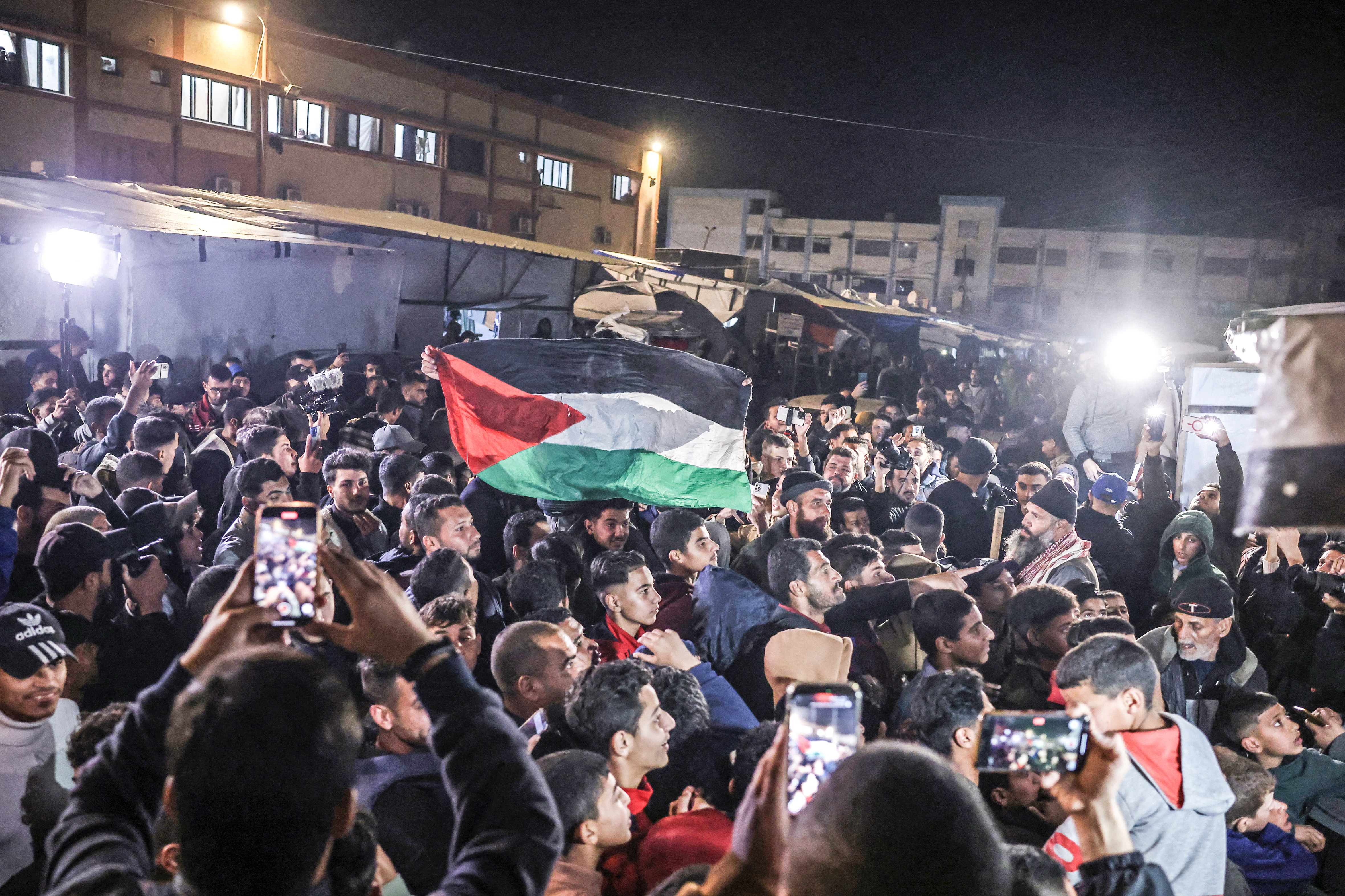 People watch a television along a street in Khan Younis