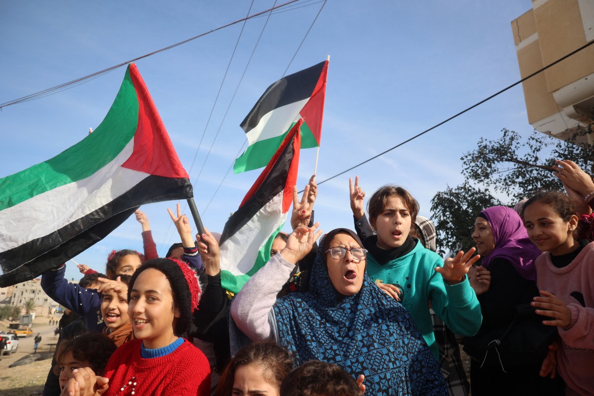 Displaced Palestinians waving national flags cheer as they return to Rafah.