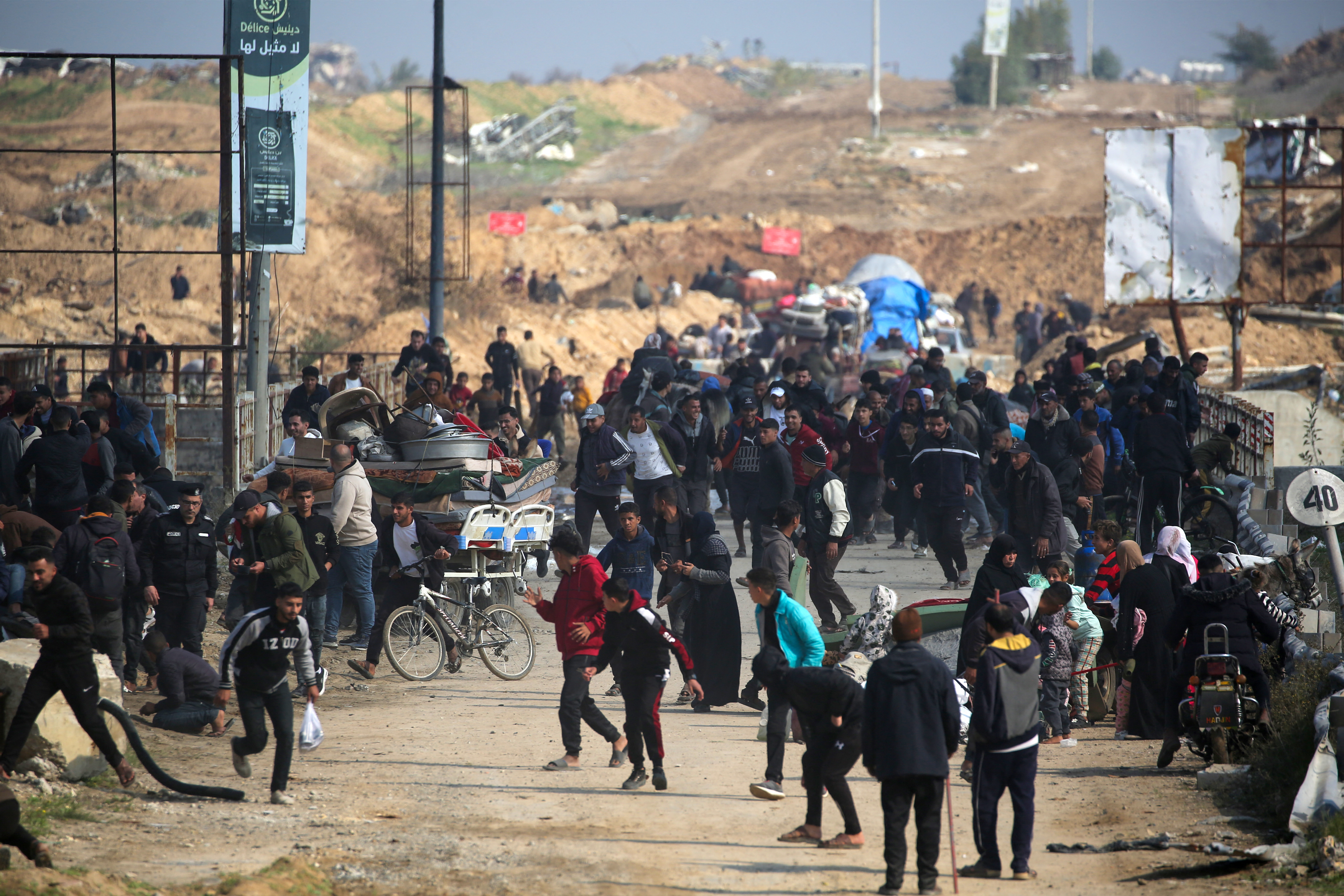Displaced Palestinians run for cover during warning shots fired by the Israeli army as they walk towards Gaza City as they cross the Netzarim corridor from the southern Gaza Strip on January 27, 2025. An unending stream of people marched up the coast of Gaza on January 27, carrying their belongings in plastic bags and repurposed flour sacks through the central city of Nuseirat after Israel reopened access to the territory's north. (Photo by Eyad BABA / AFP)