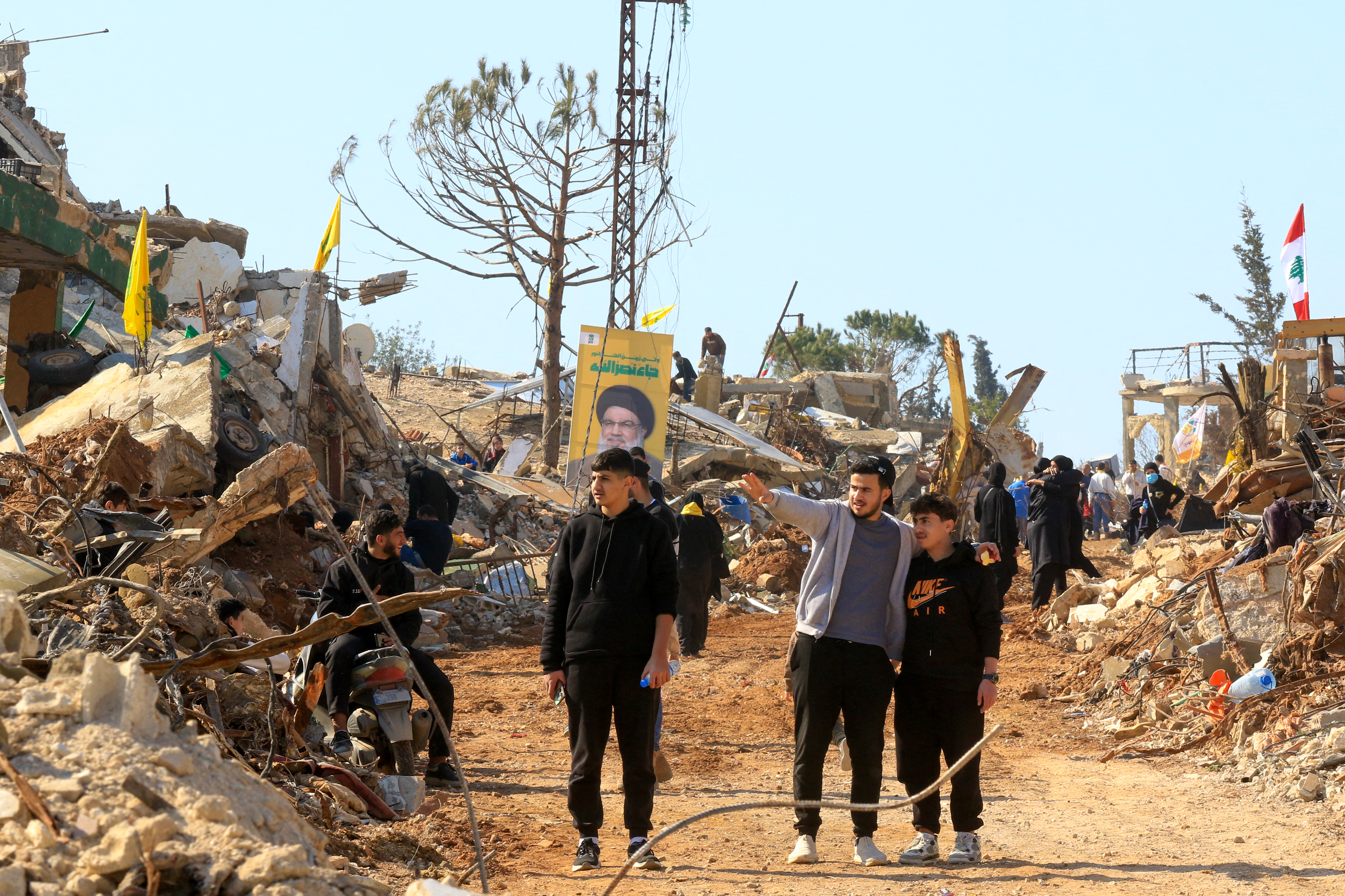 People inspect the damage as they walks past the rubble of buildings destroyed during the Israeli air and ground offensive in the southern Lebanese village of Aita al-Shaab, near the border with Israel on January 27, 2025. South Lebanon residents accompanied by the army tried to return to their villages on January 27, official media and AFP correspondents reported, a day after Israeli fire killed more than 20 people in the area. (Photo by Mahmoud ZAYYAT / AFP)