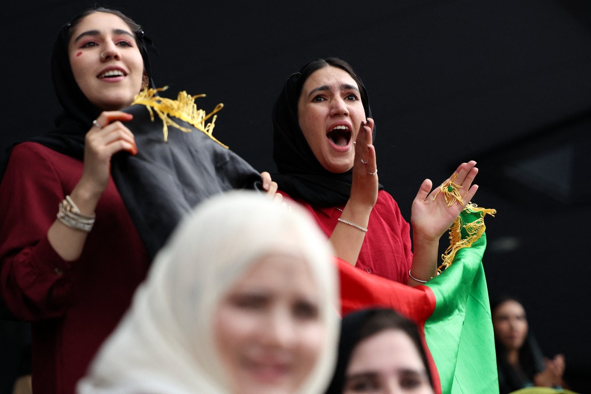 Fans cheer in the stands with the flag of the former Islamic Republic of Afghanistan