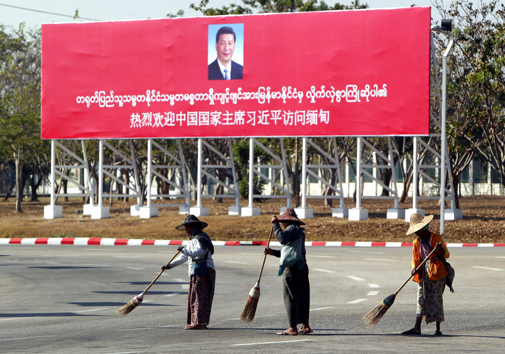 Municipal workers sweep on a road near a welcoming billboard to Chinese President Xi Jinping Friday, Jan. 17, 2020, in Naypyitaw, Myanmar. China's President Xi Jinping was heading to Myanmar on Friday for a state visit likely to deepen the countries' already close bilateral relations at a critical time. (AP Photo/Aung Shine Oo)