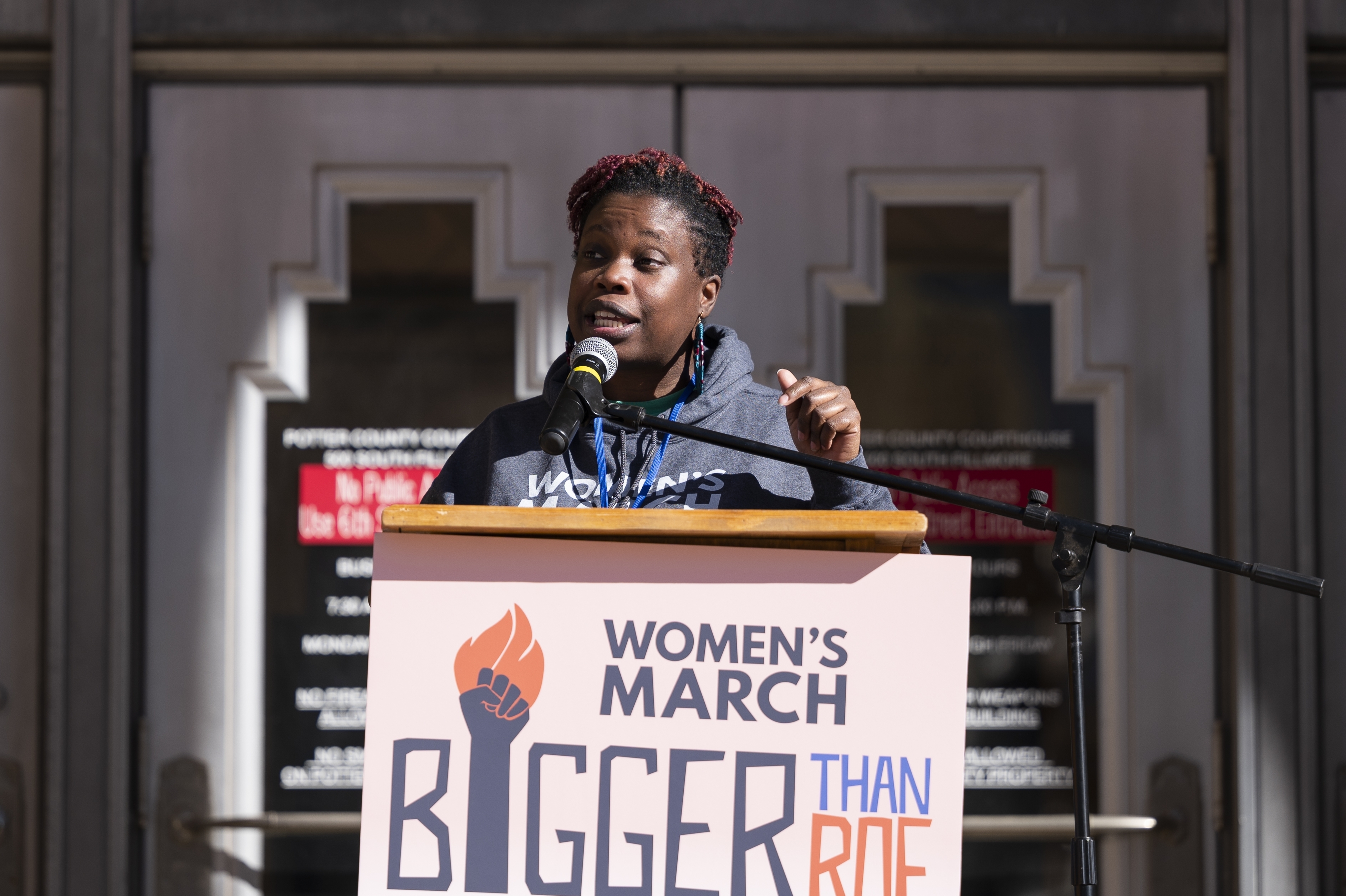 Tamika Middleton speaks at a podium with the Women's March logo