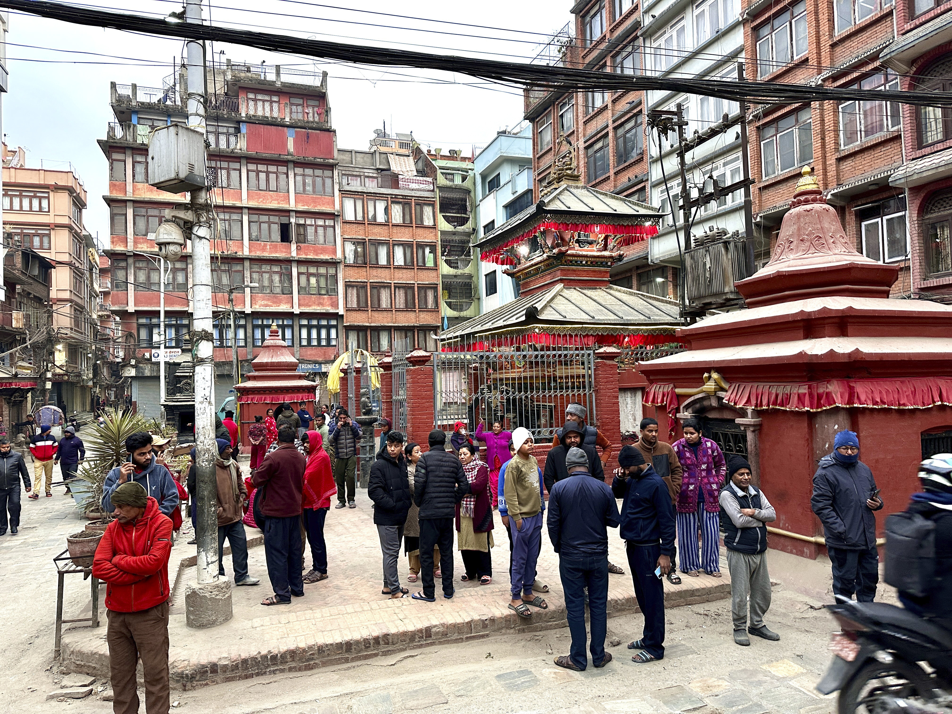 Nepalese people stand after rushing out of their homes after experiencing an earthquake in Kathmandu, Nepal, Tuesday