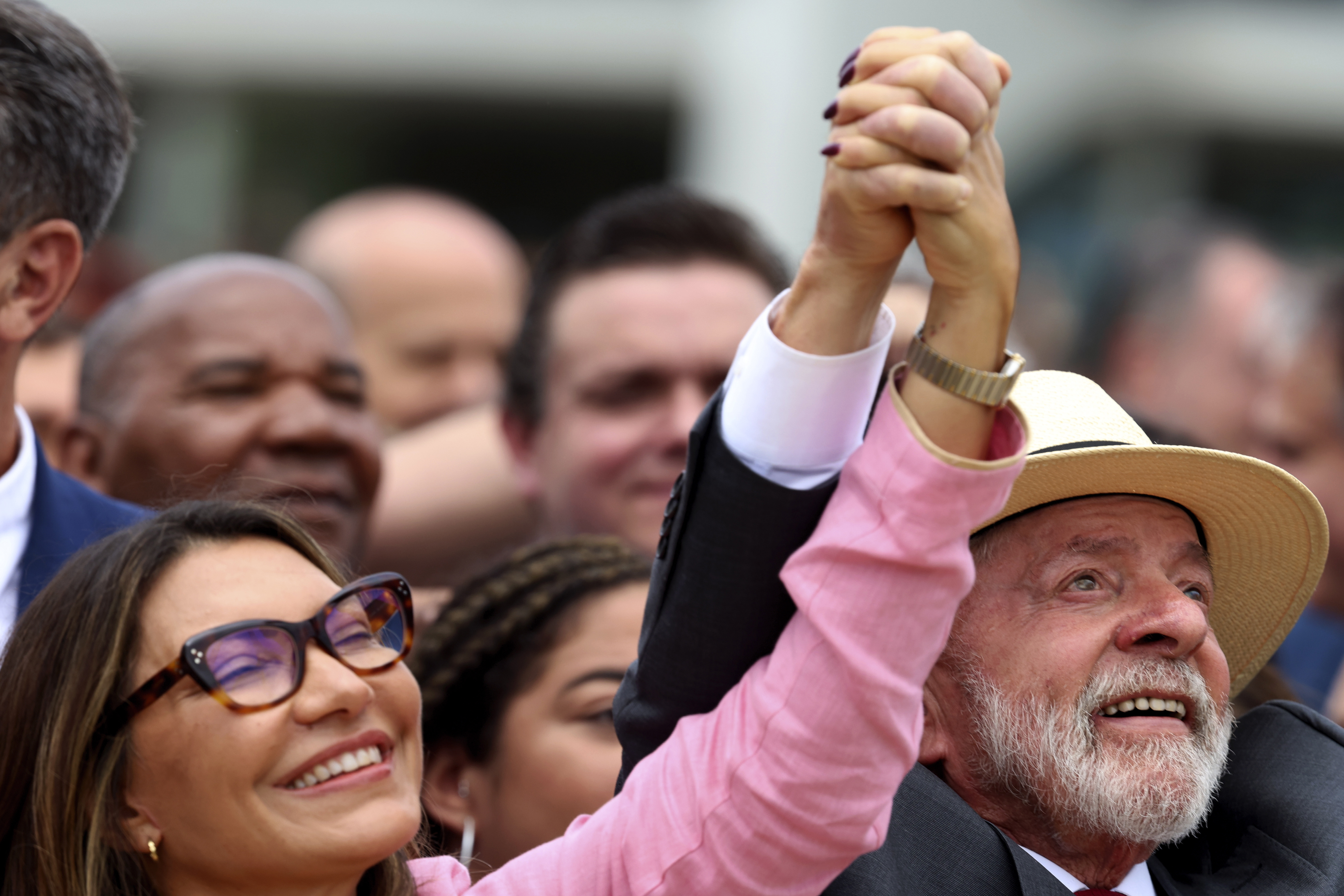 President Lula holds raises his and his wife's hands at a celebration to mark the second anniversary of an attack in Brasilia.