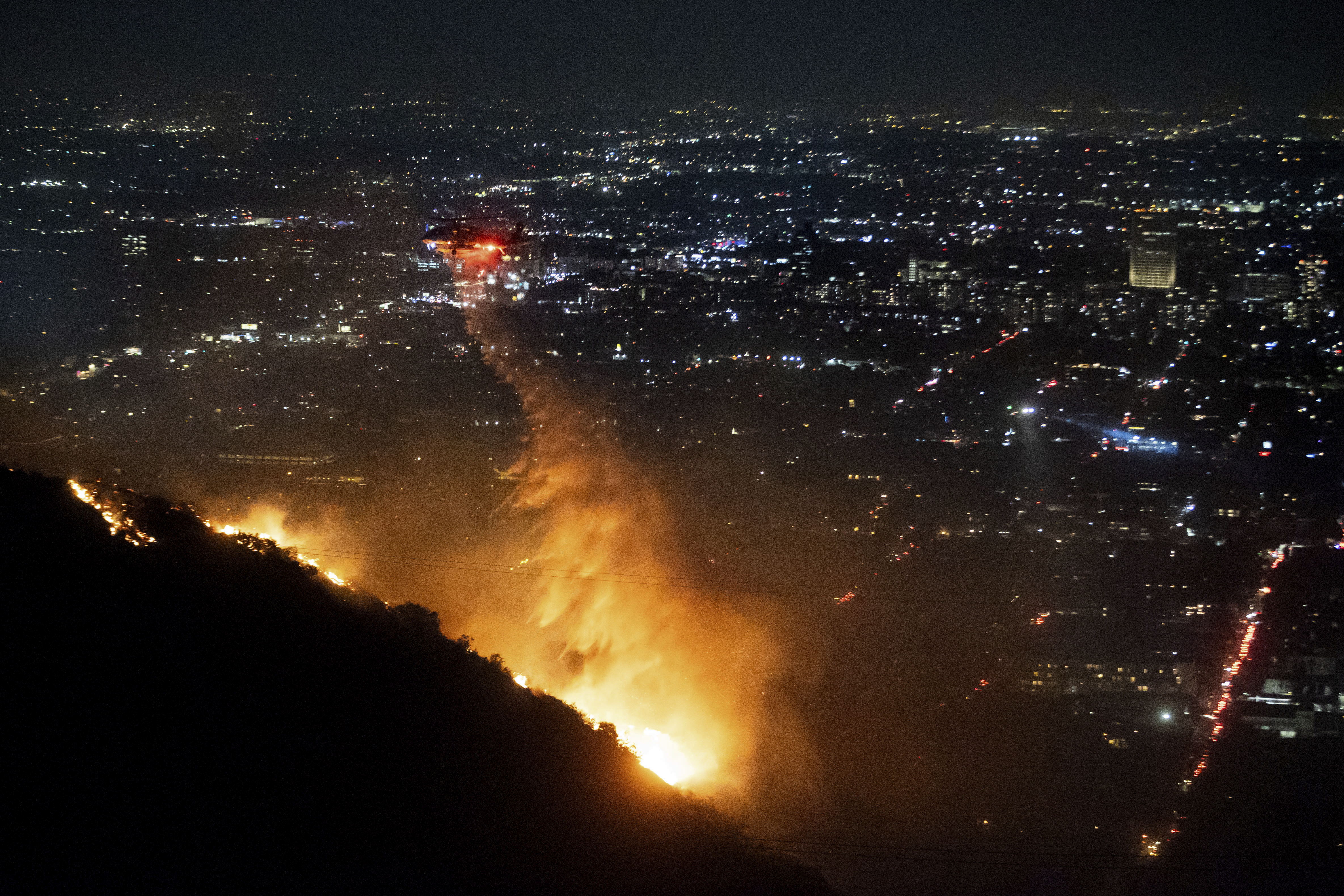 Water is dropped by helicopter on the burning Sunset Fire in the Hollywood Hills section of Los Angeles, Wednesday, Jan. 8