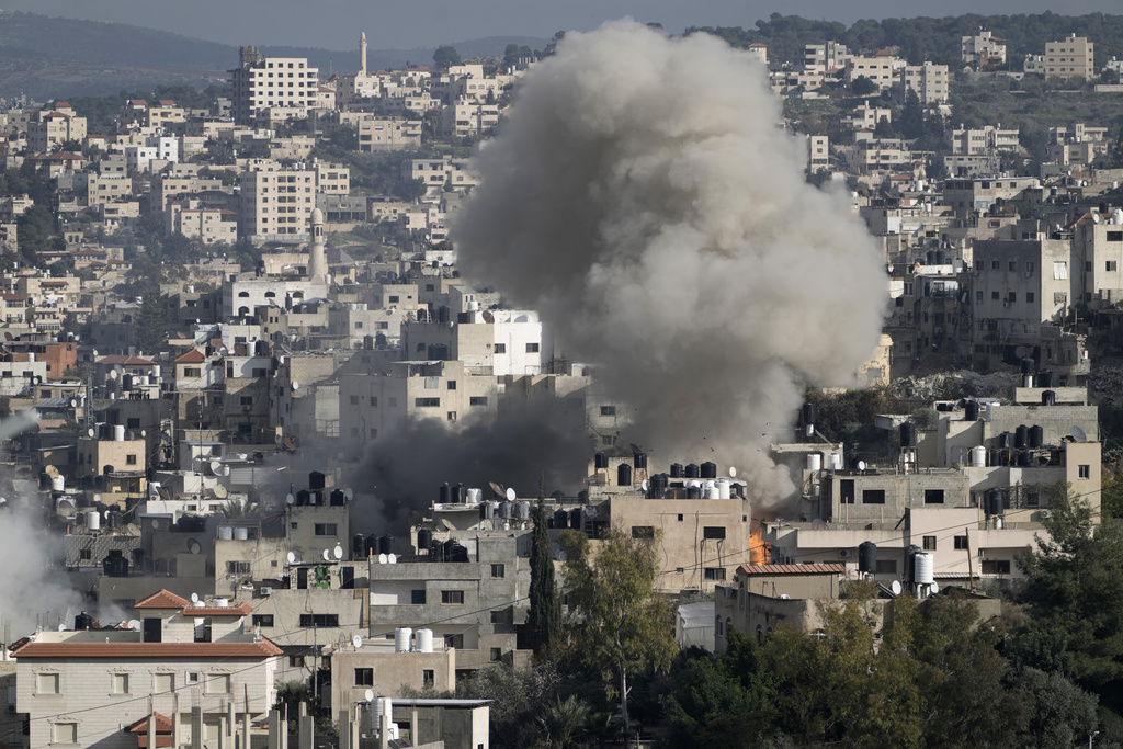 Smoke billows from an explosion as homes are demolished.