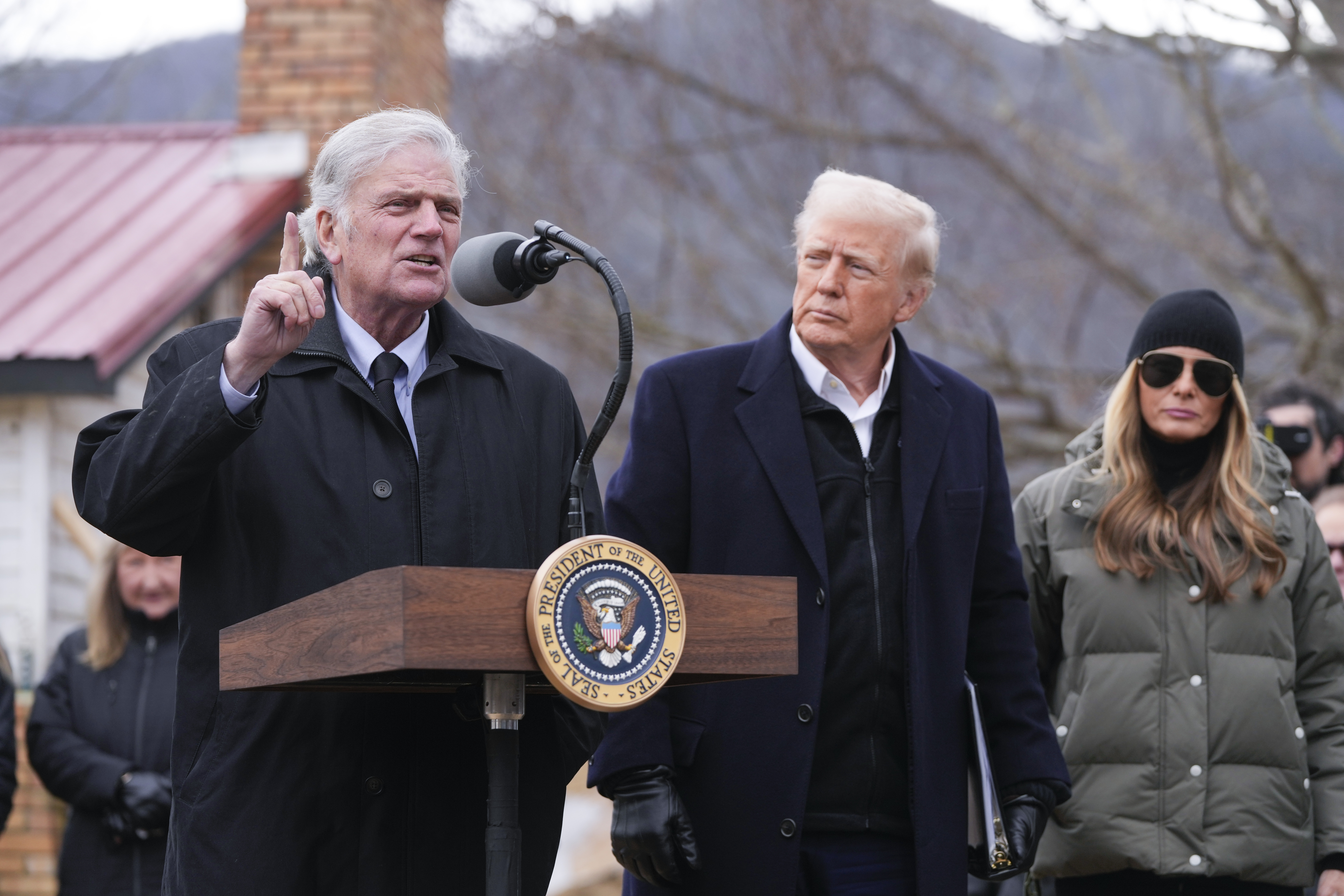 Franklin Graham speaks at a presidential podium next to Donald Trump in Swannanoa, North Carolina.
