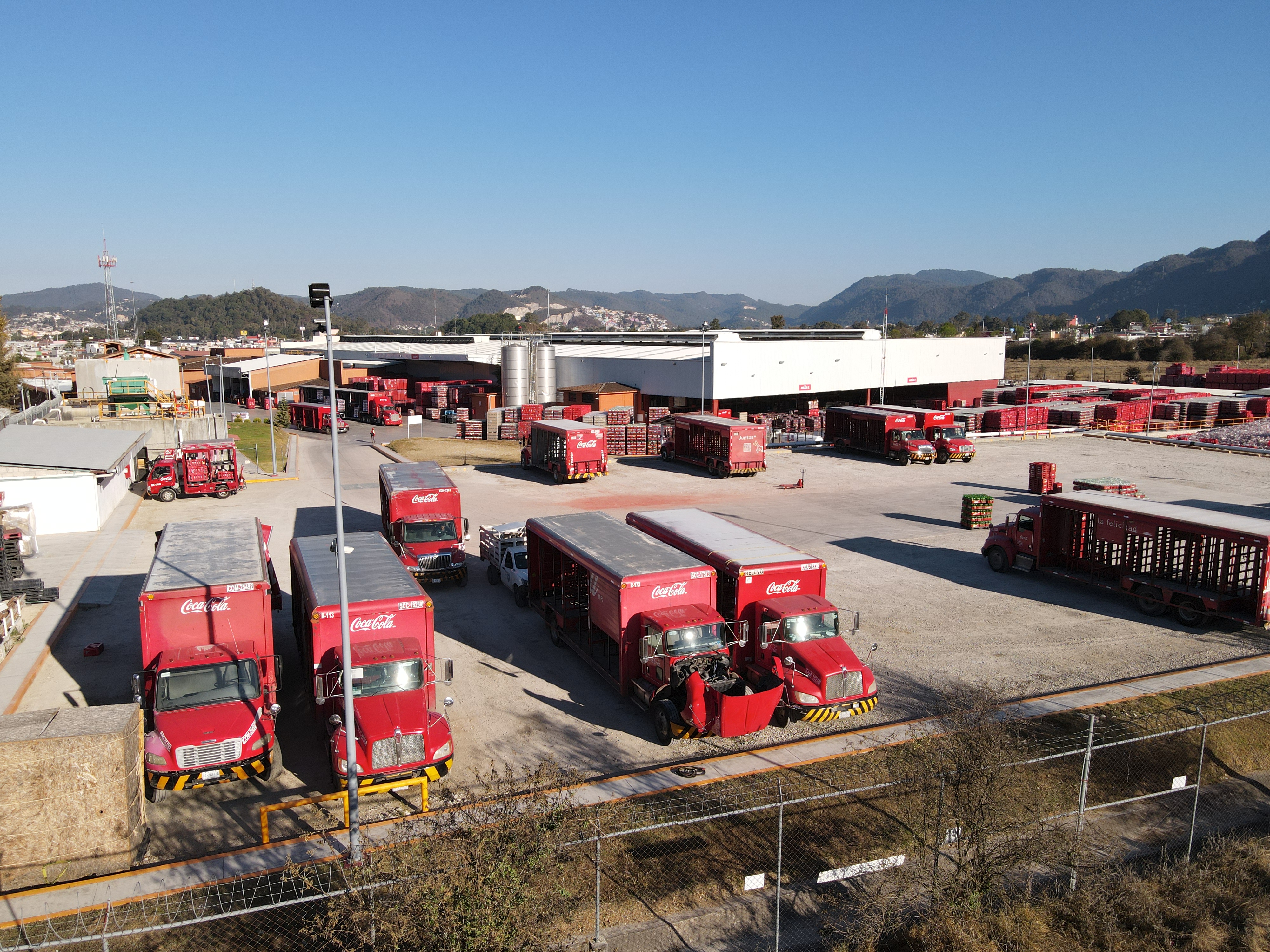 An aerial view of a Coca-Cola bottling plant, with trucks parked out front