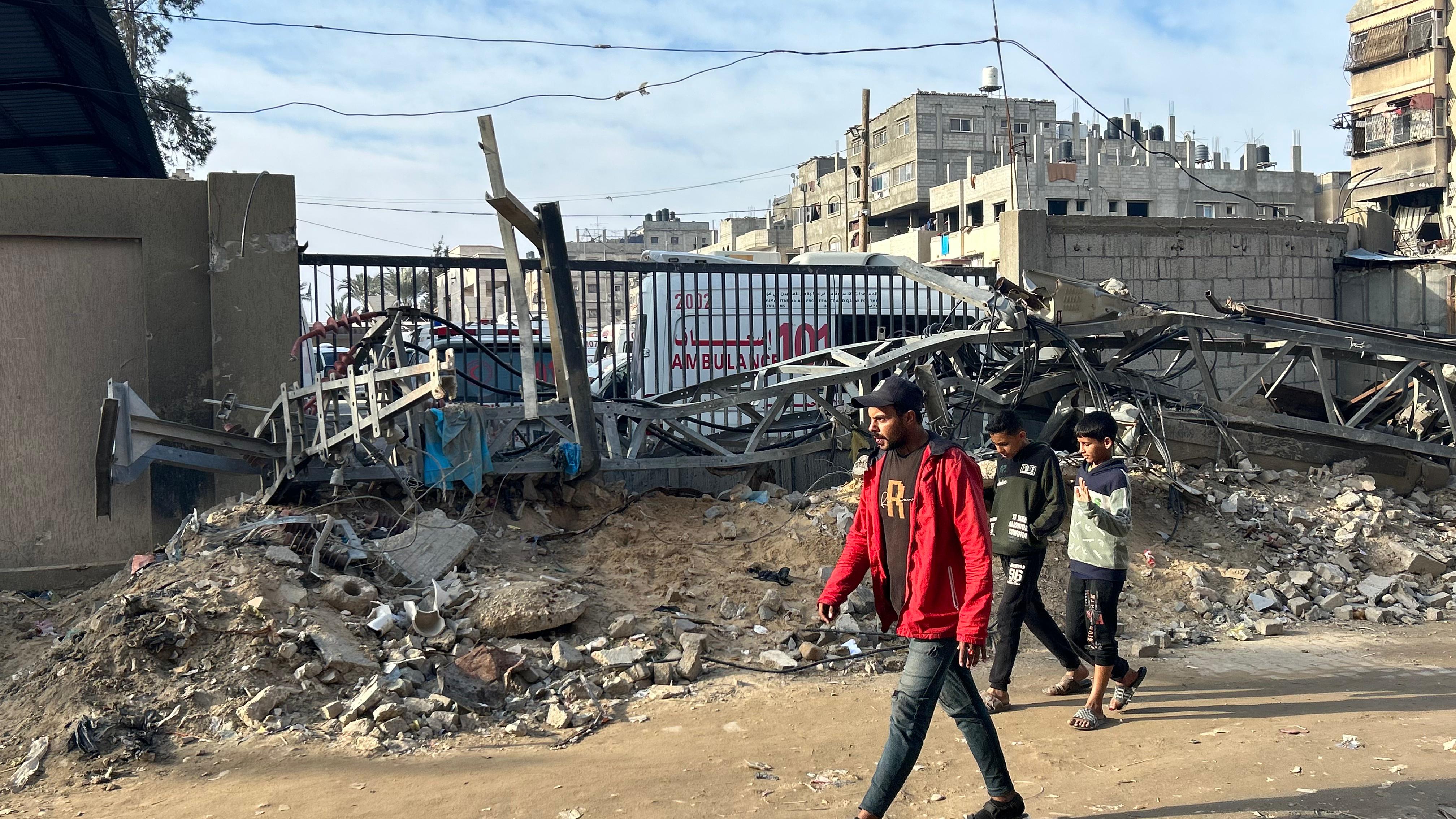 Man walking past rubble outside of hospital 