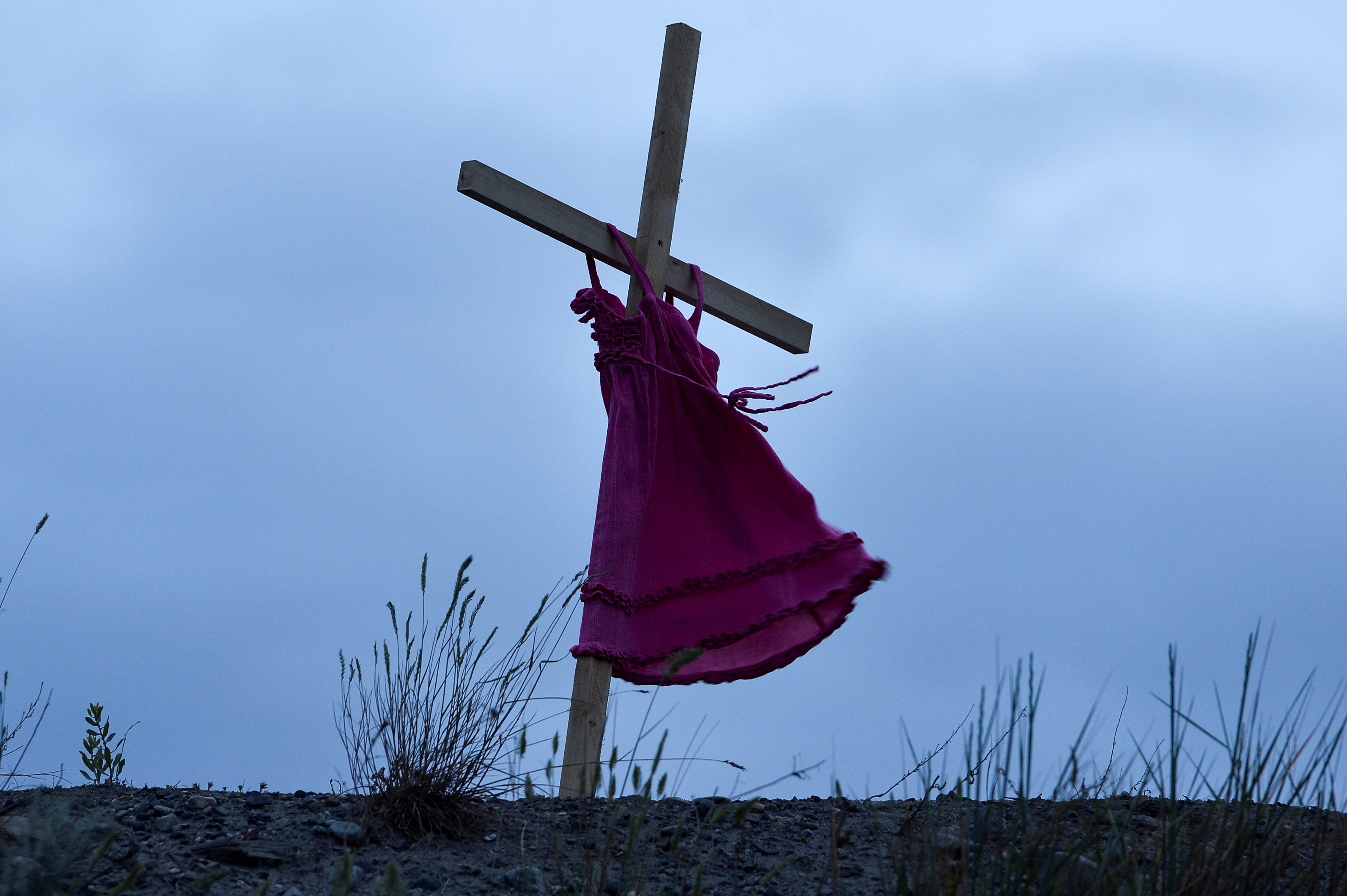 A child's red dress hangs on a stake near the grounds of Kamloops Indian Residential School