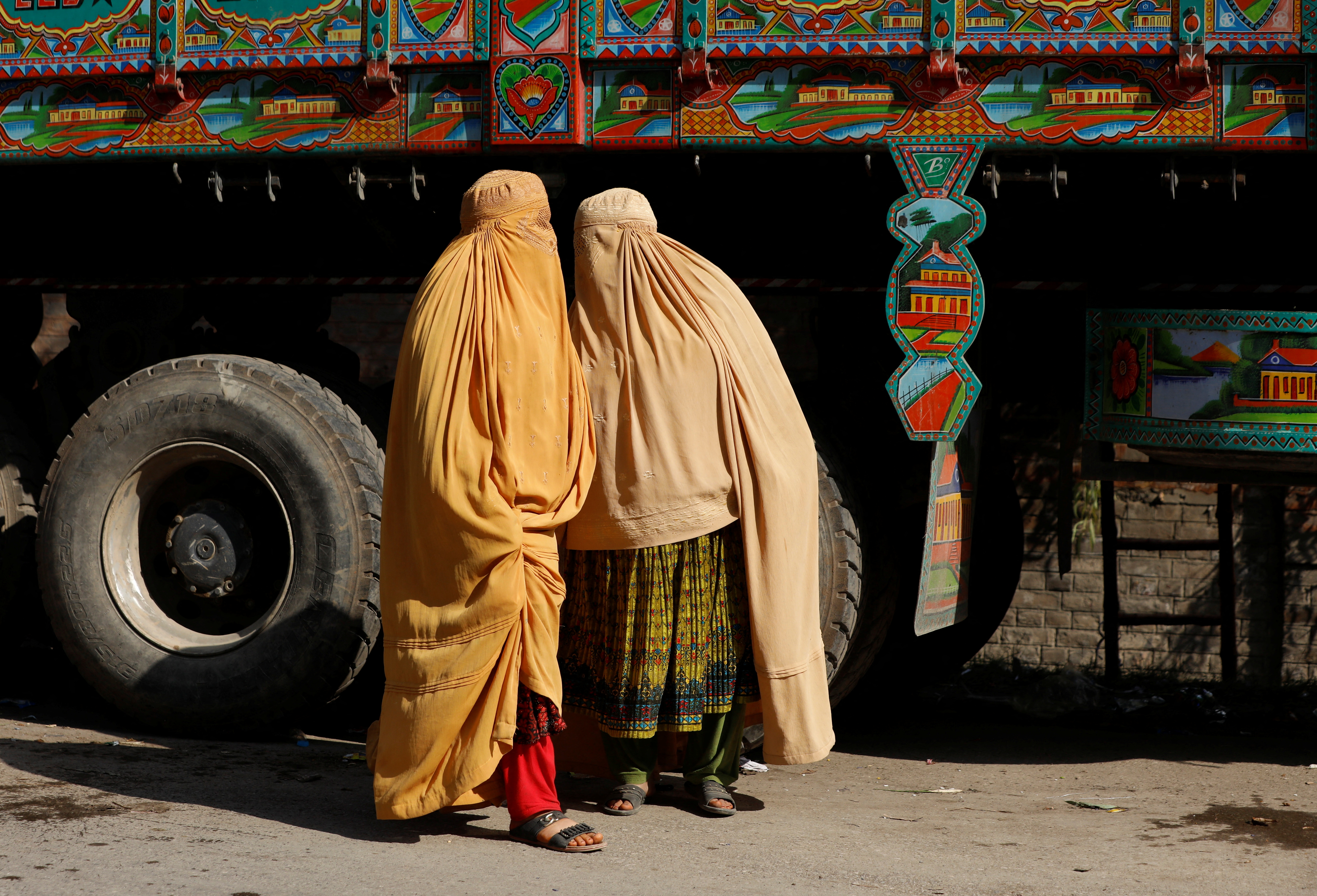 Afghan women in burqa stand with a truck loaded with belongings as they return home, after Pakistan gives last warning to undocumented immigrants to leave, outside the United Nations High Commissioner for Refugees (UNHCR) repatriation centre in Azakhel town in Nowshera, Pakistan November 3, 2023. REUTERS/Fayaz Aziz