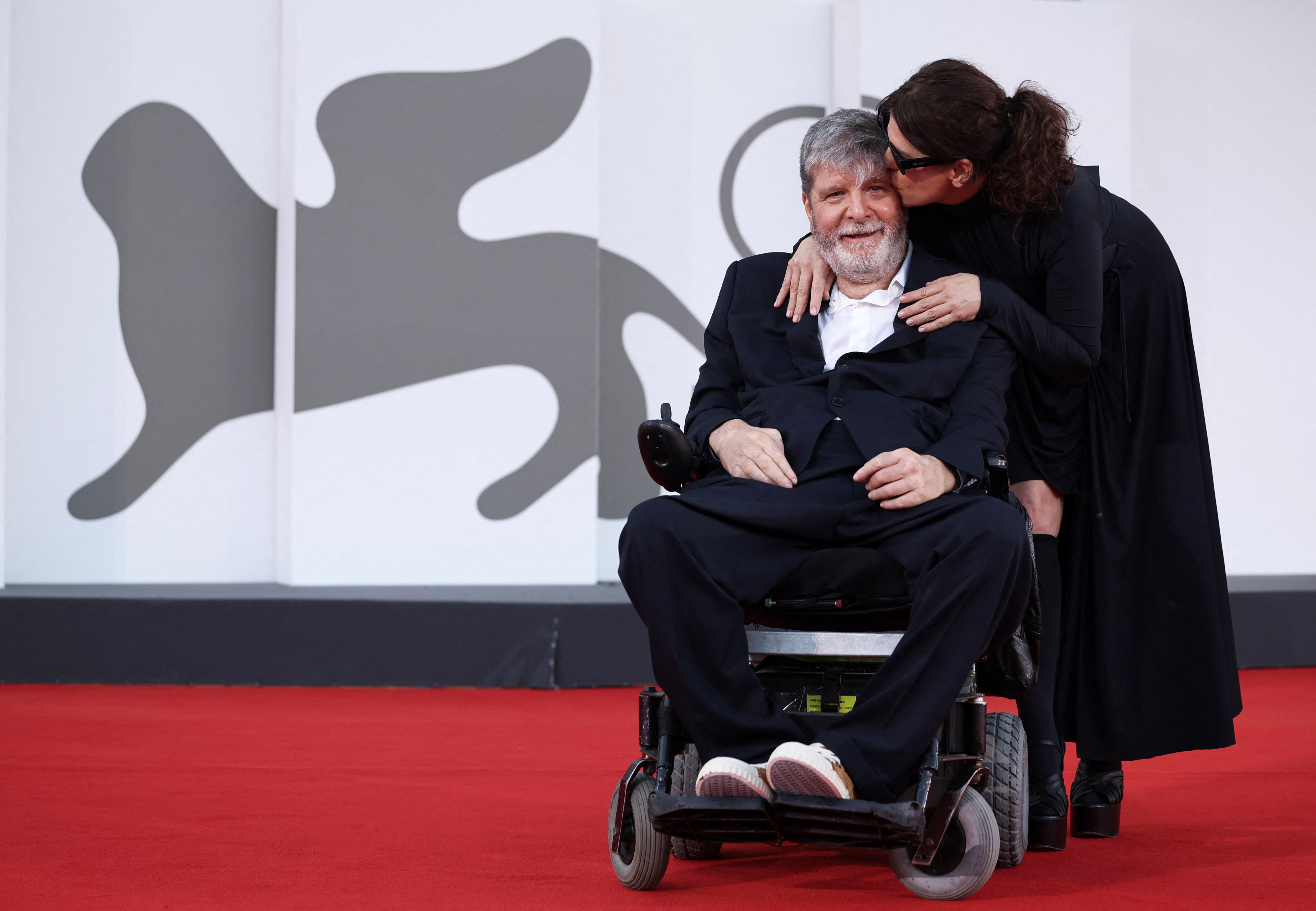 Barbara Paz gives Marcelo Rubens Paiva a kiss on the red carpet at the Venice Film Festival