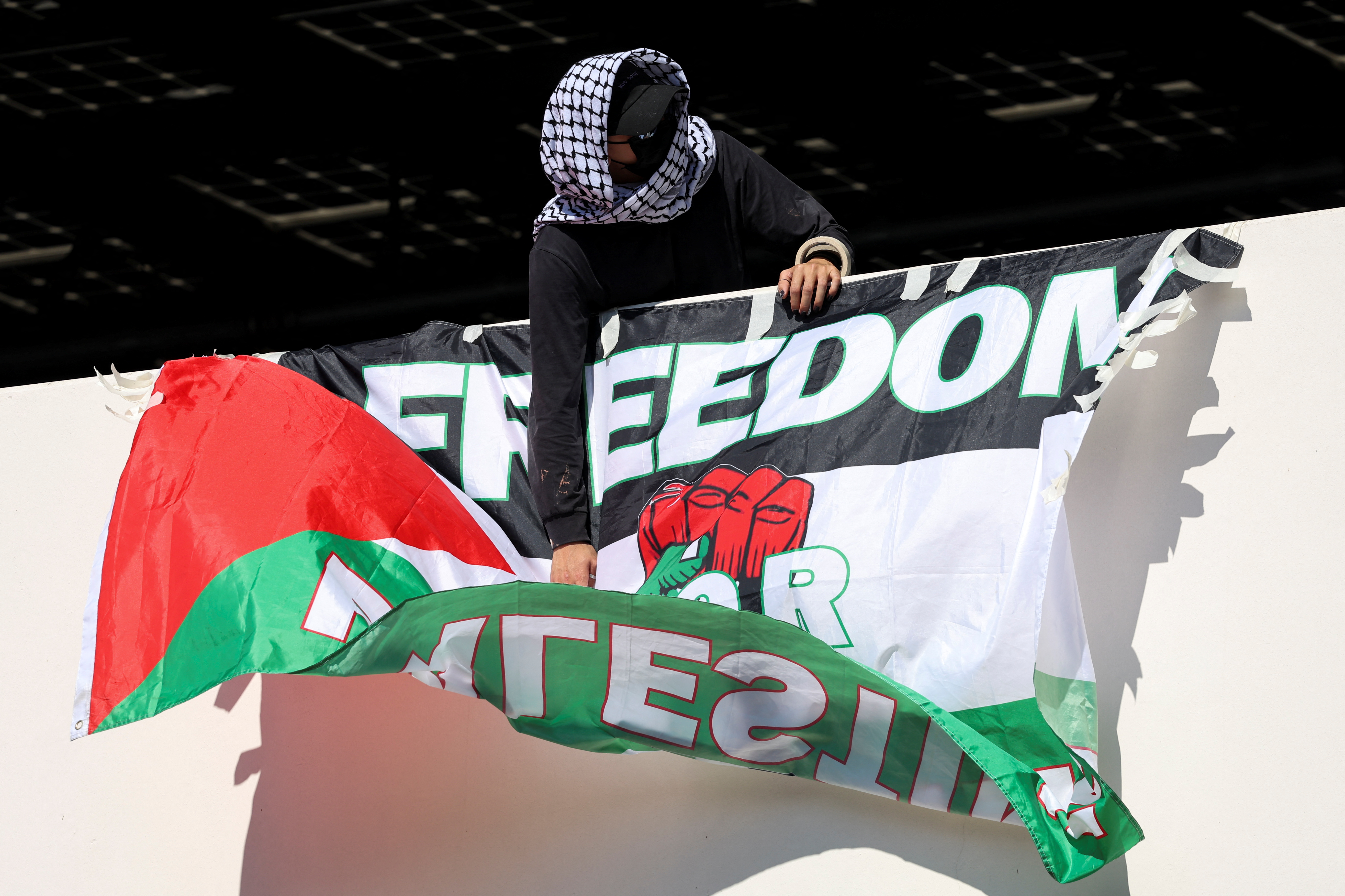 A protester hangs a pro-Palestinian banner on a University of California
