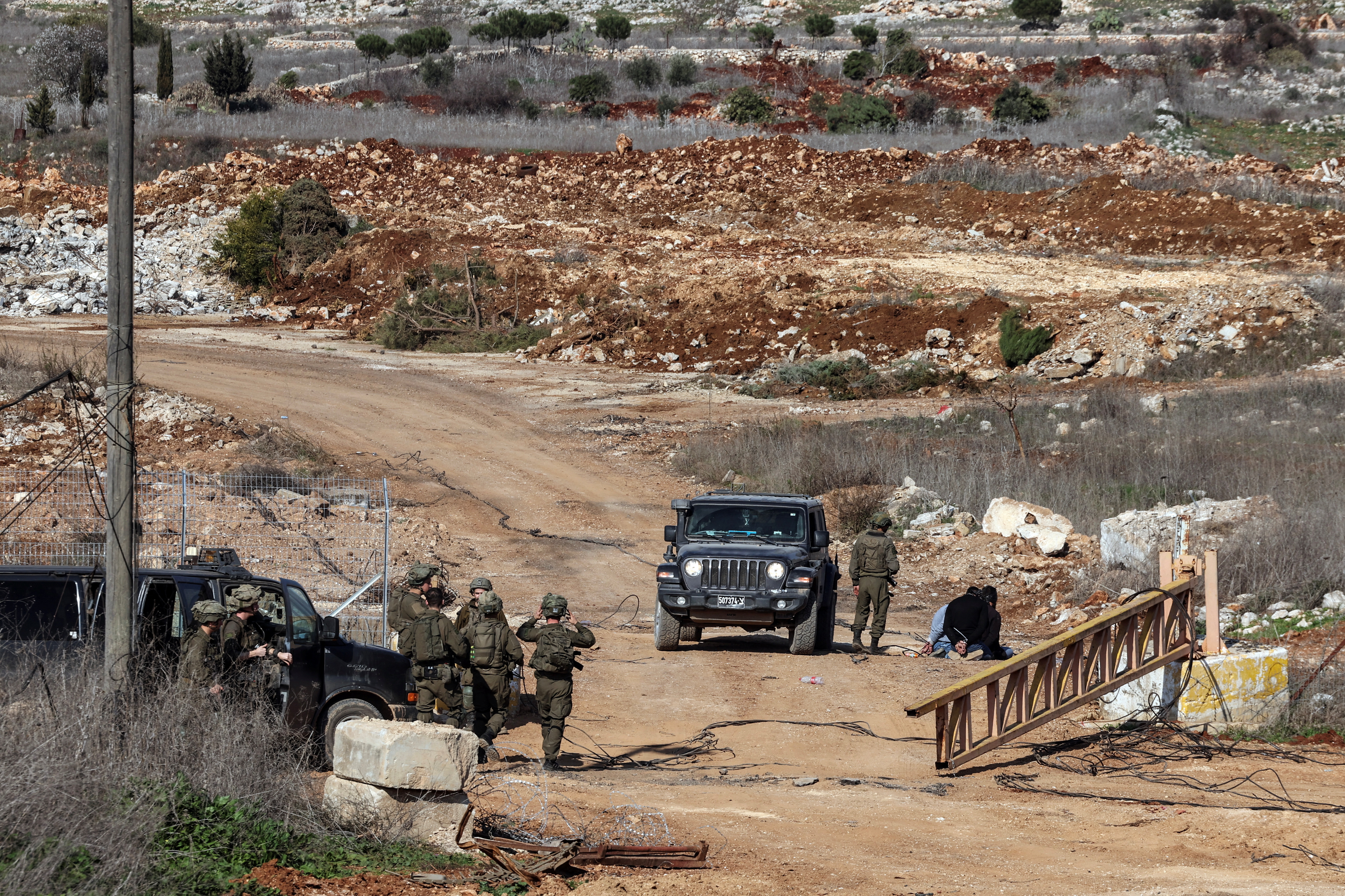 Israeli soldiers stand near Lebanese detainees at the Israeli-Lebanese border, as seen from northern Israel, after a ceasefire between Israel and Hezbollah took effect, January 27, 2025. REUTERS/Ronen Zvulun