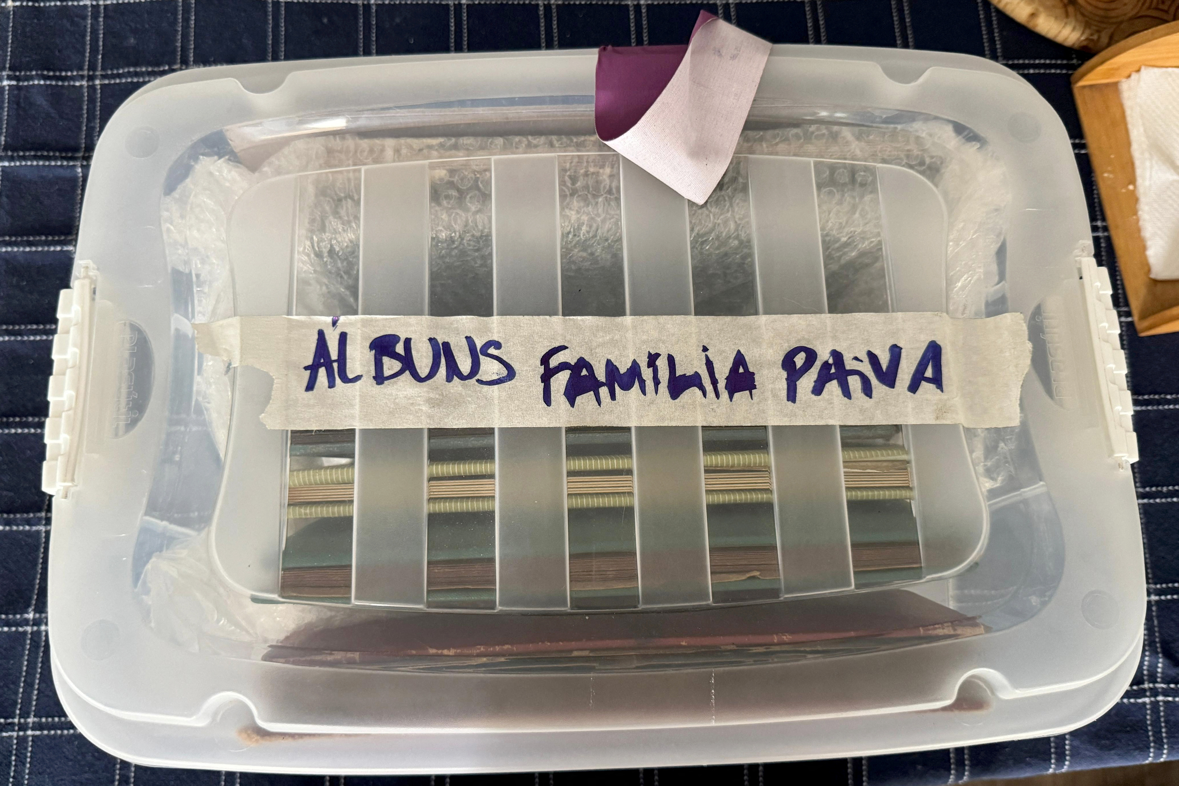 A Tupperware plastic box of photo albums labeled with masking tape: 
