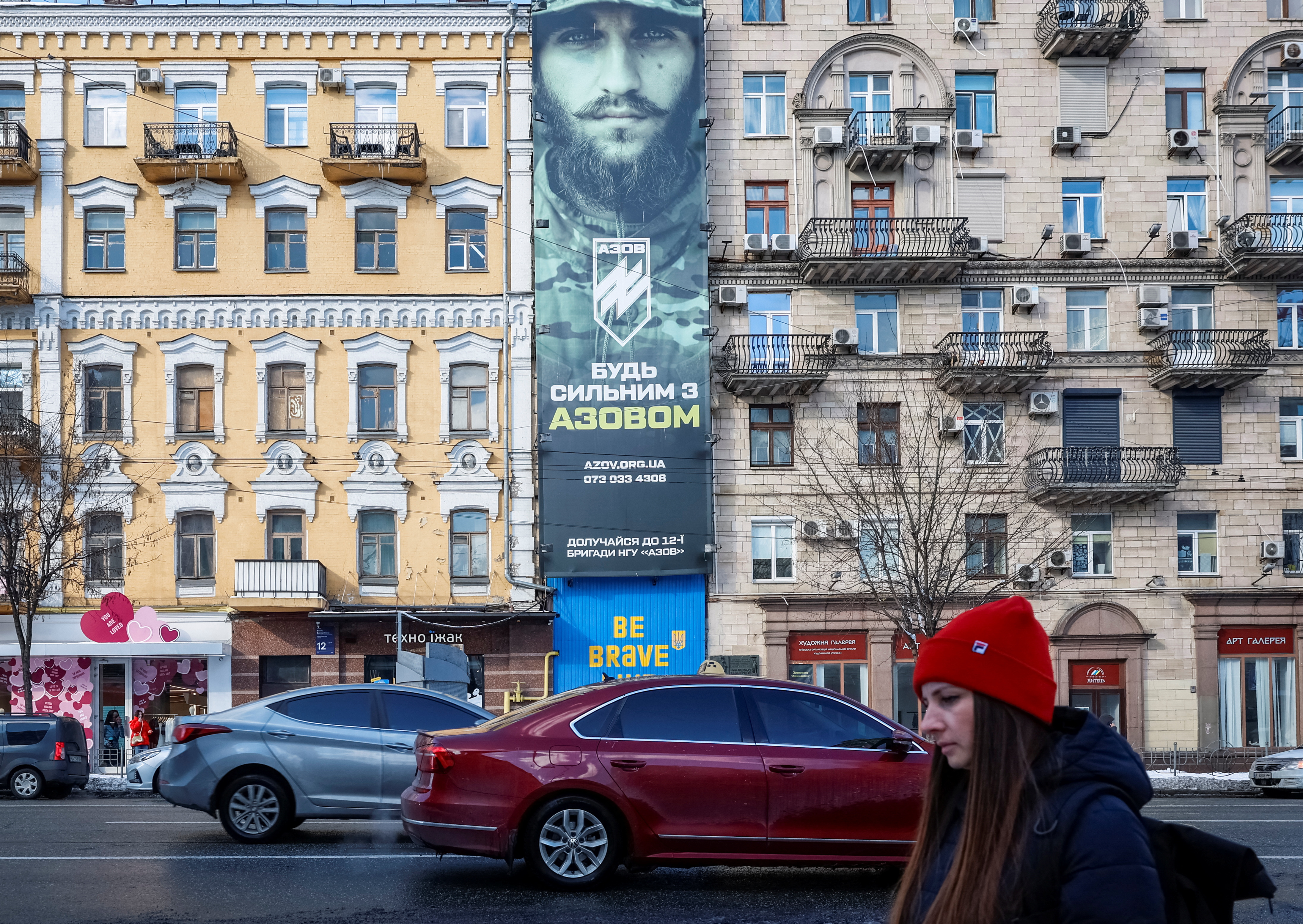 A woman walks near a banner advertising an appeal to join security forces of Ukraine, in Kyiv