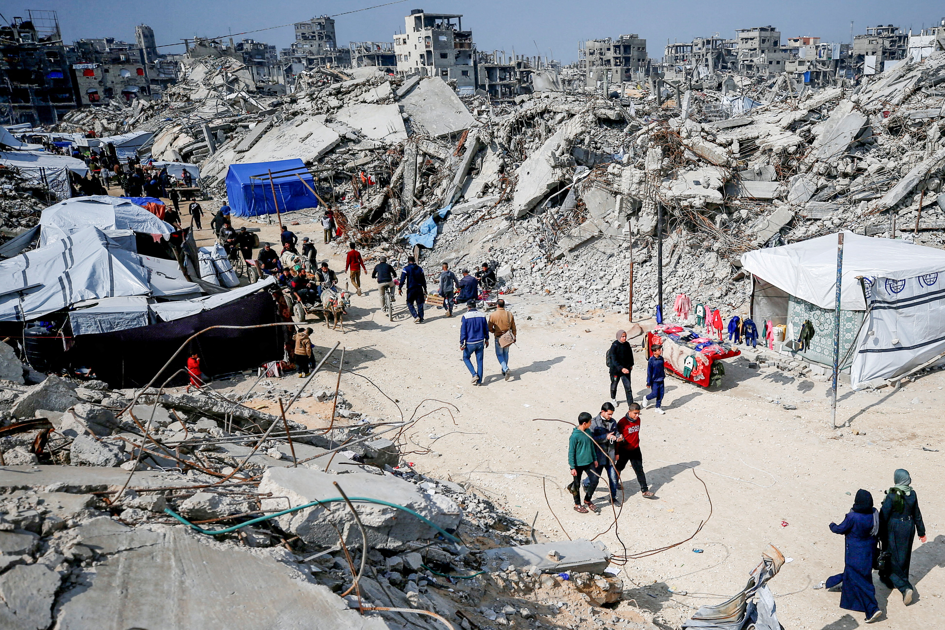 Palestinians walk on a street among the rubble [File: Mahmoud Issa/Reuters]