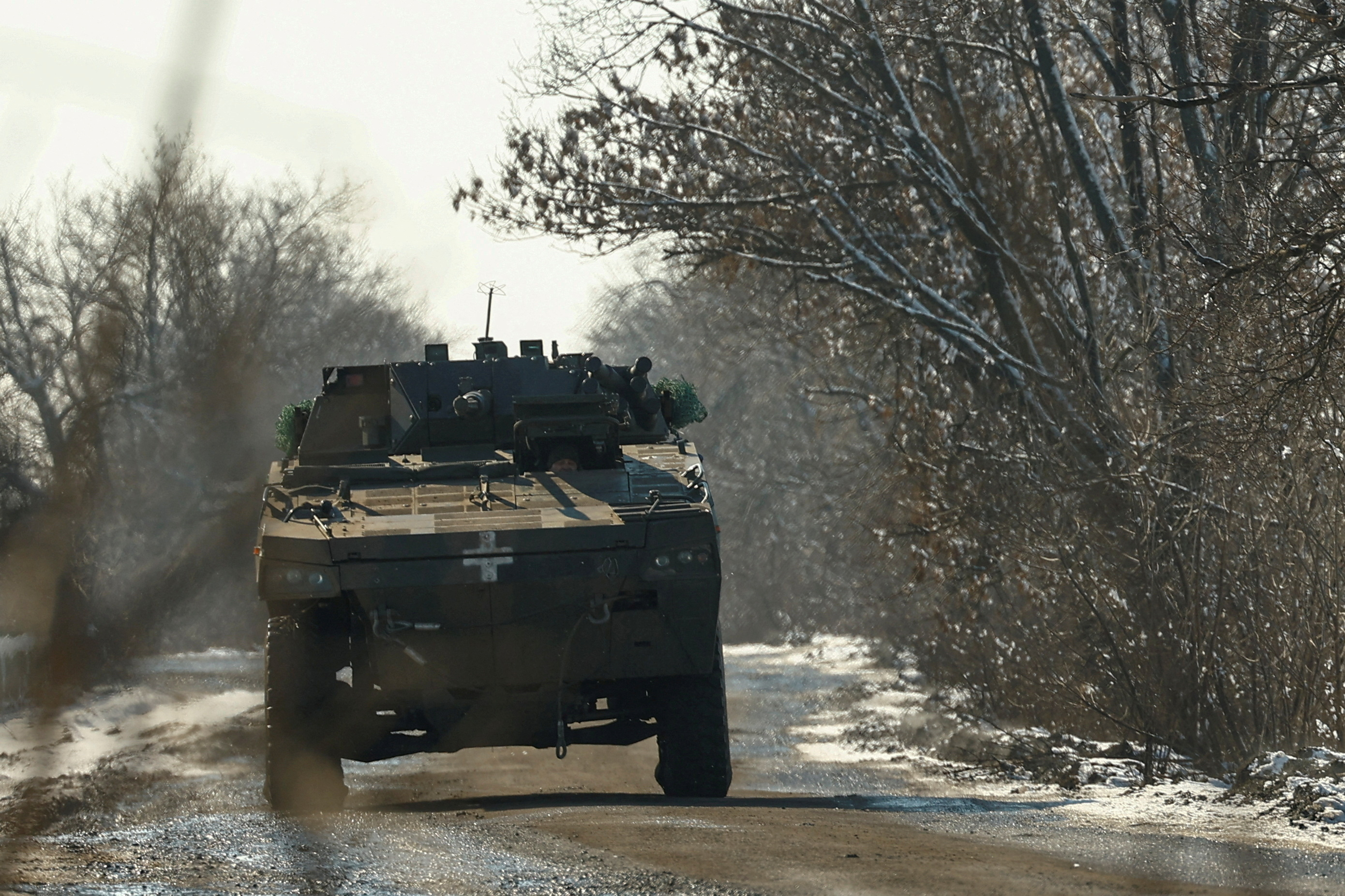 A Ukrainian serviceman drives a Rosomak armoured personnel carrier along a road.