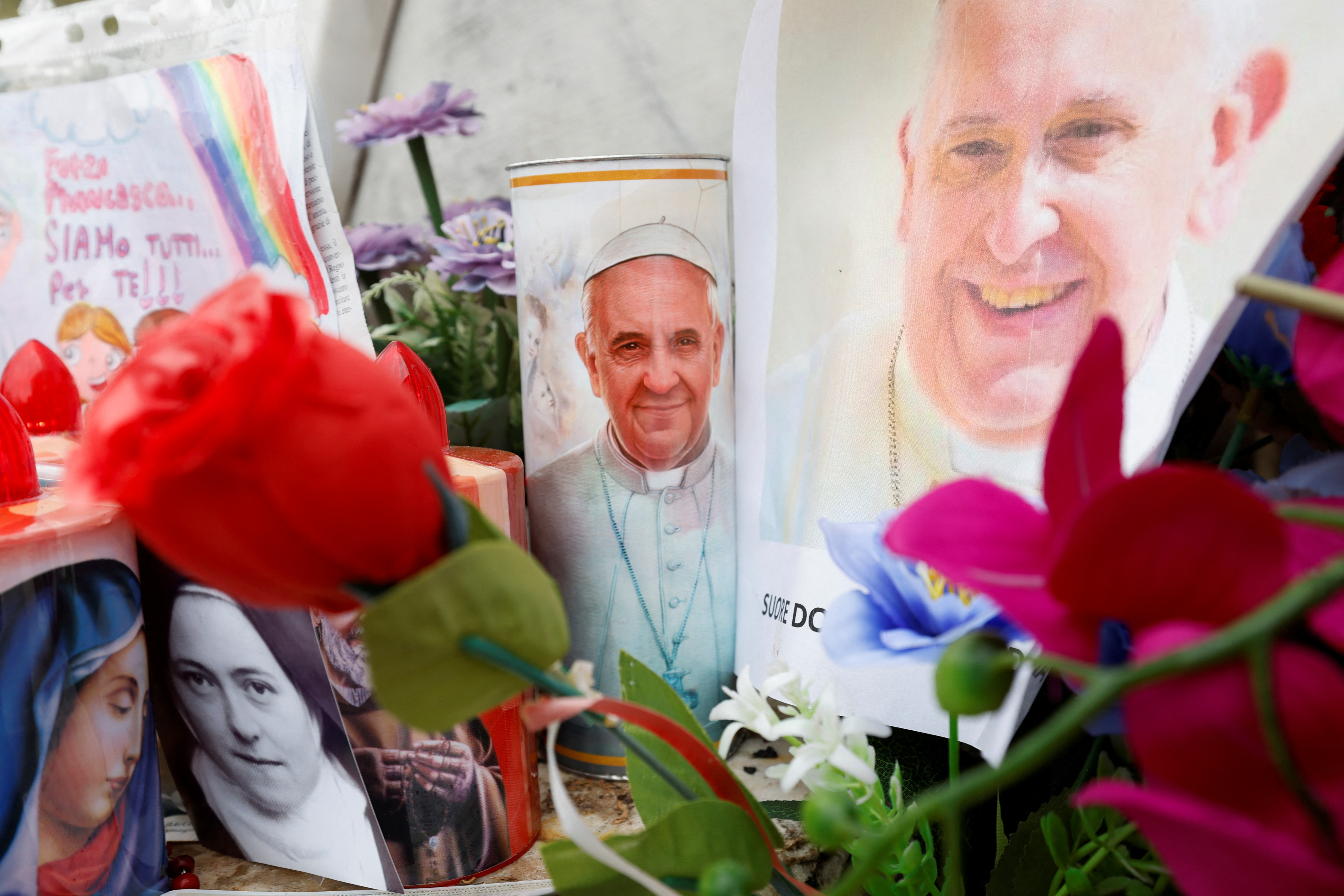 Candles and pictures of Pope Francis as people pray for his health