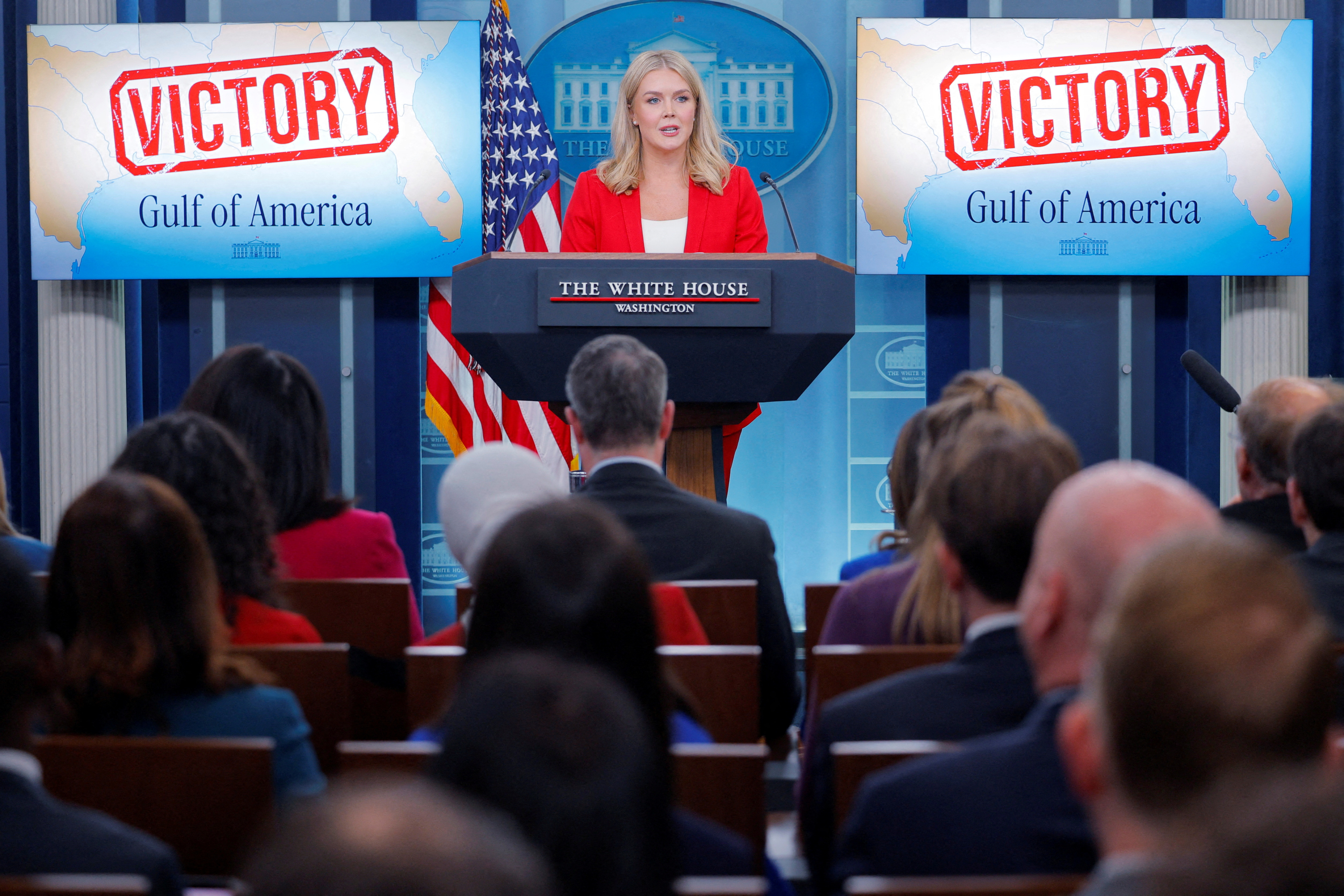 White House Press Secretary Karoline Leavitt speaks next to TV screens displaying the word "Victory" after a judge ruled against the Associated Press' request for a temporary restraining order, during a press briefing at the White House in Washington, DC, U.S., February 25, 2025. REUTERS/Brian Snyder TPX IMAGES OF THE DAY