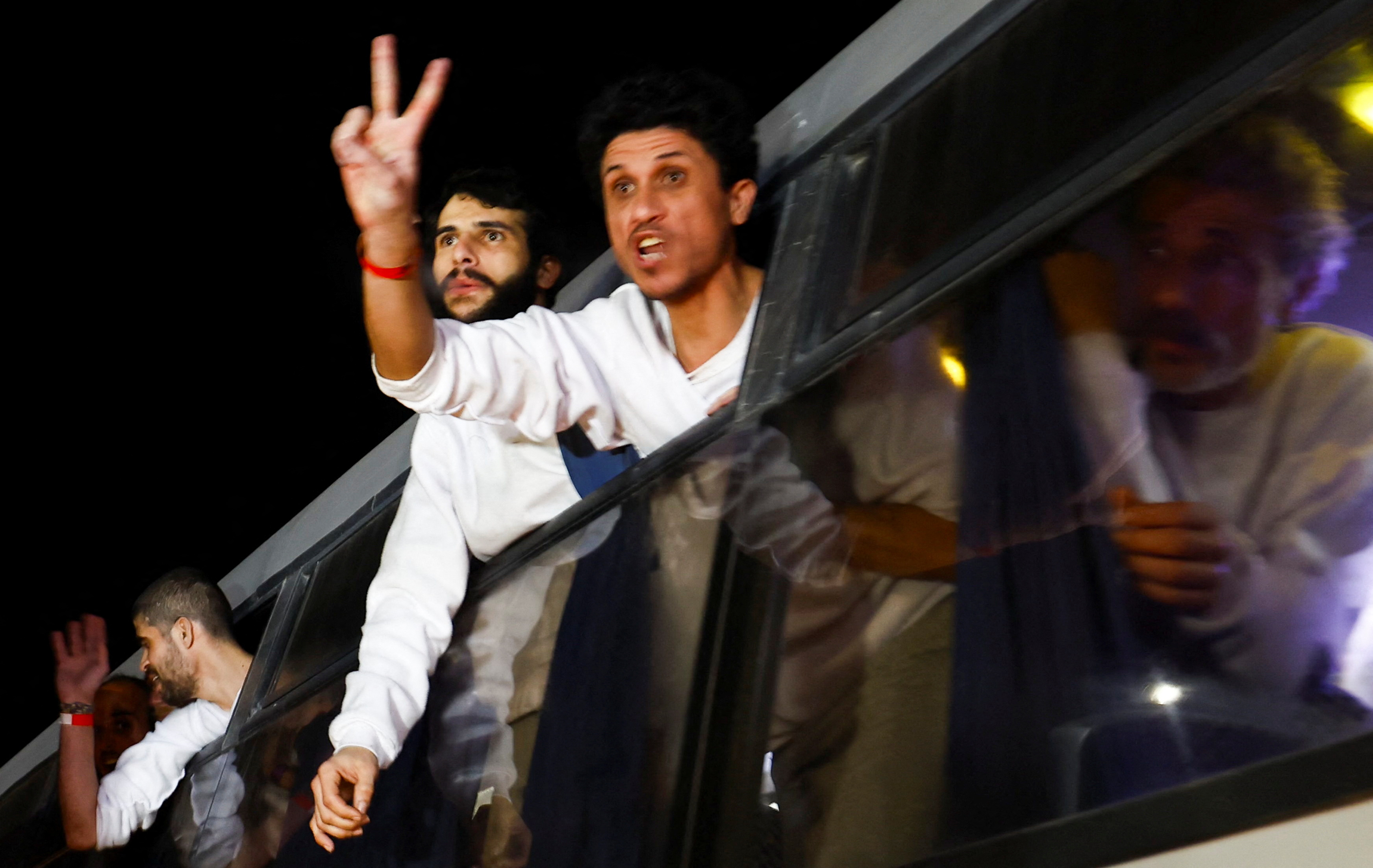 Freed Palestinian prisoners look out of the windows as they arrive in a bus after being released from an Israeli jail as part of a ceasefire and a hostages-prisoners swap deal between Hamas and Israel,