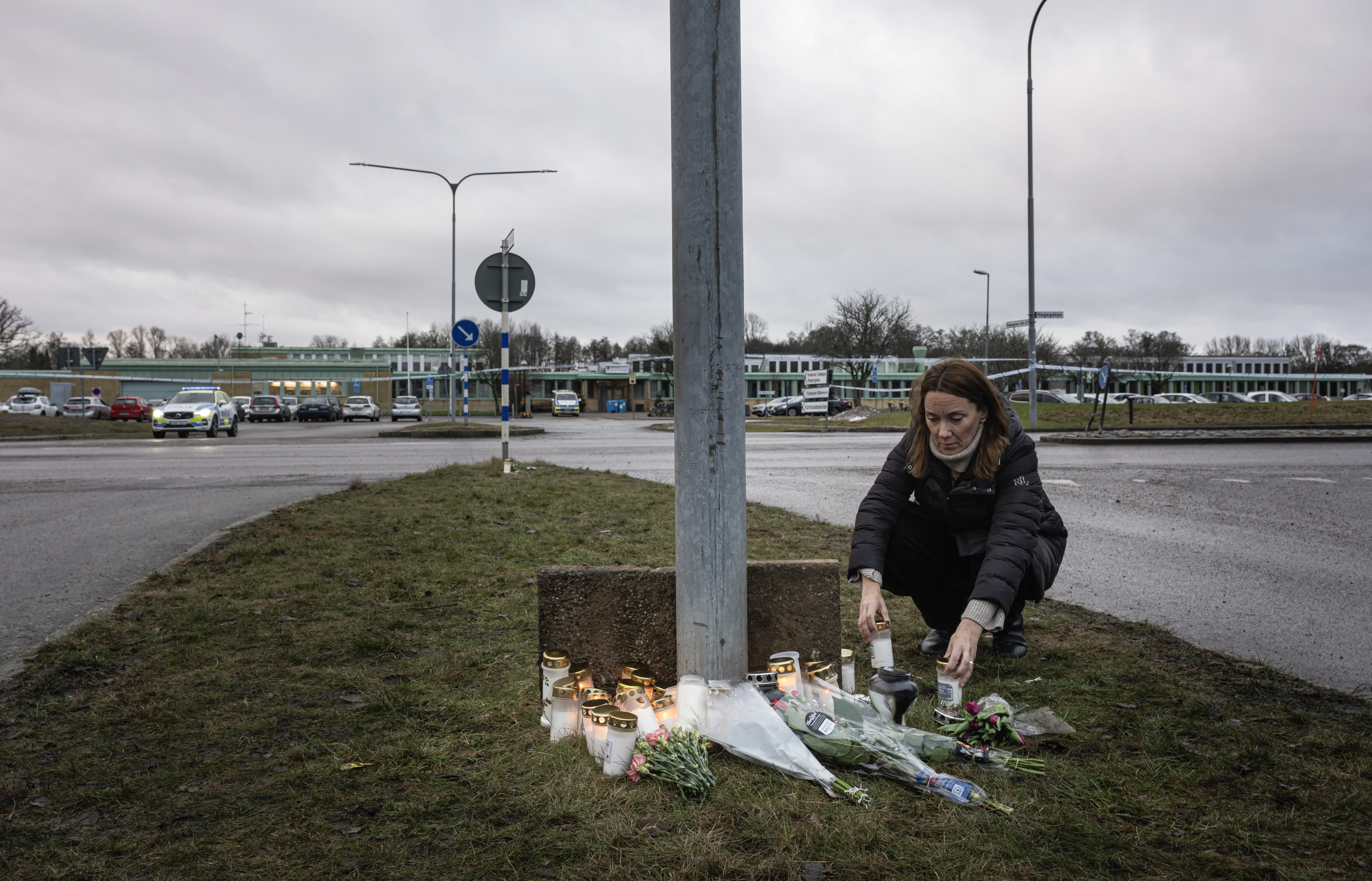 A woman lights candles at a makeshift vigil in Orebro, Sweden, on February 5, 2025 after a shooting at the adult education center Campus Risbergska school, where eleven people were killed.