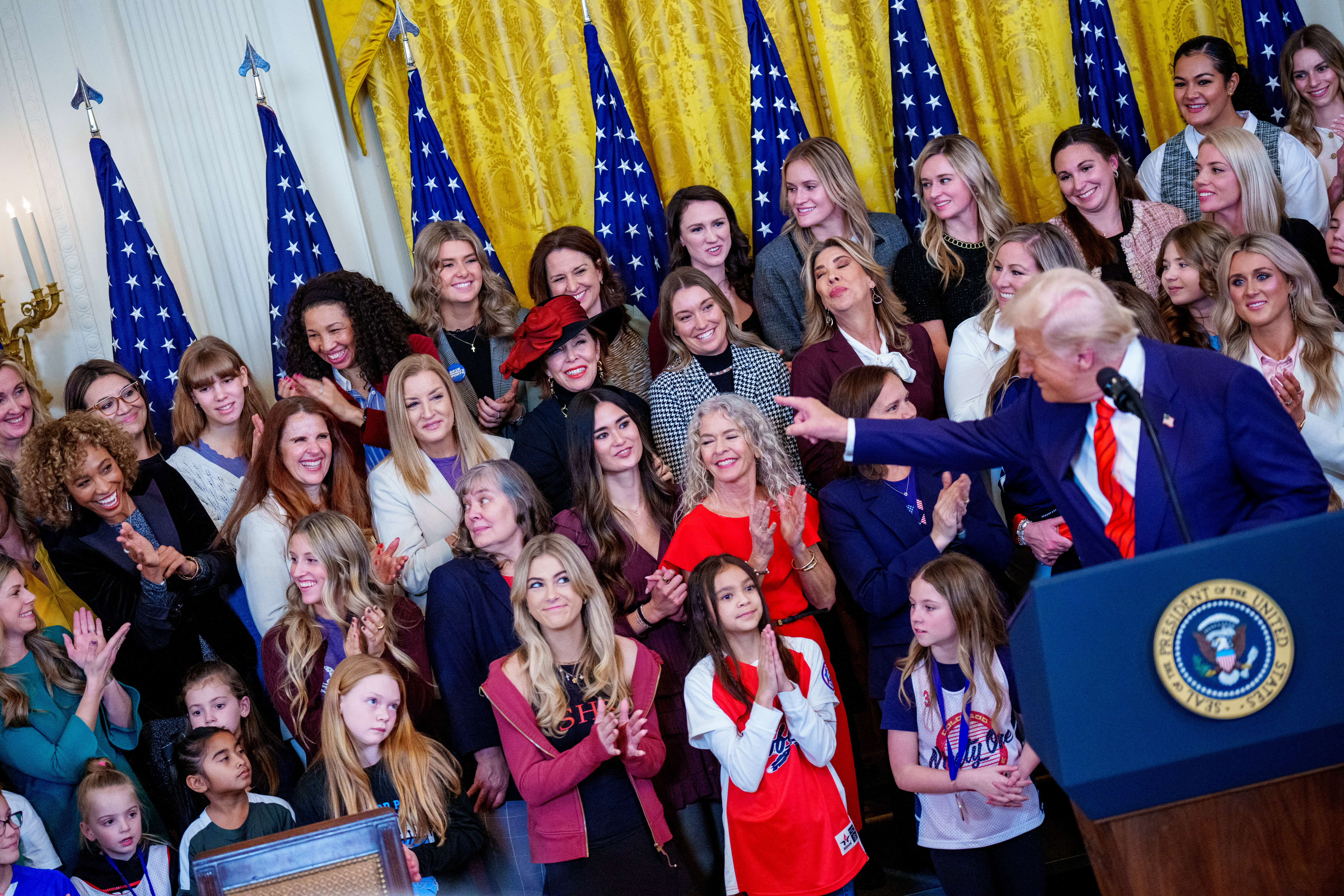 WASHINGTON, DC - FEBRUARY 05: Sage Steele (L) reacts while standing behind U.S. President Donald Trump as he recognizes her before he signs the "No Men in Women's Sports" executive order in the East Room of the White House on February 5, 2025 in Washington, DC. The executive order, which Trump signed on National Girls and Women in Sports Day, prohibits transgender women from competing in women's sports and is the third order he has signed that targets transgender people. Andrew Harnik/Getty Images/AFP (Photo by Andrew Harnik / GETTY IMAGES NORTH AMERICA / Getty Images via AFP)