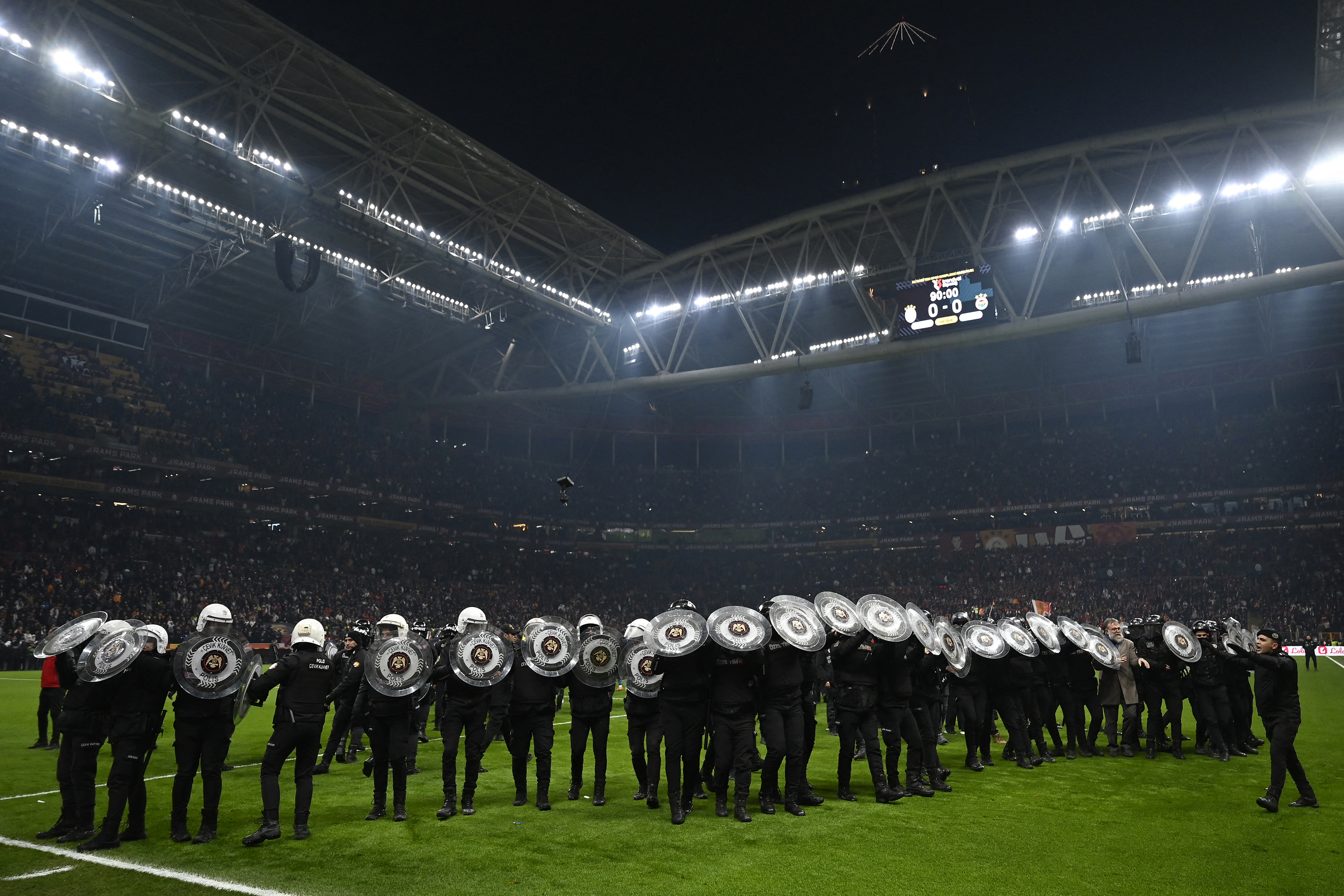 Turkish anti riot police officers hold their shields on the pitch at the end of the Turkish Super lig football match between Galatasaray and Fenerbahce at at the Ali Samiyen Sport Complext stadium in Istanbul, on February 24, 2025. (Photo by Ozan KOSE / AFP)