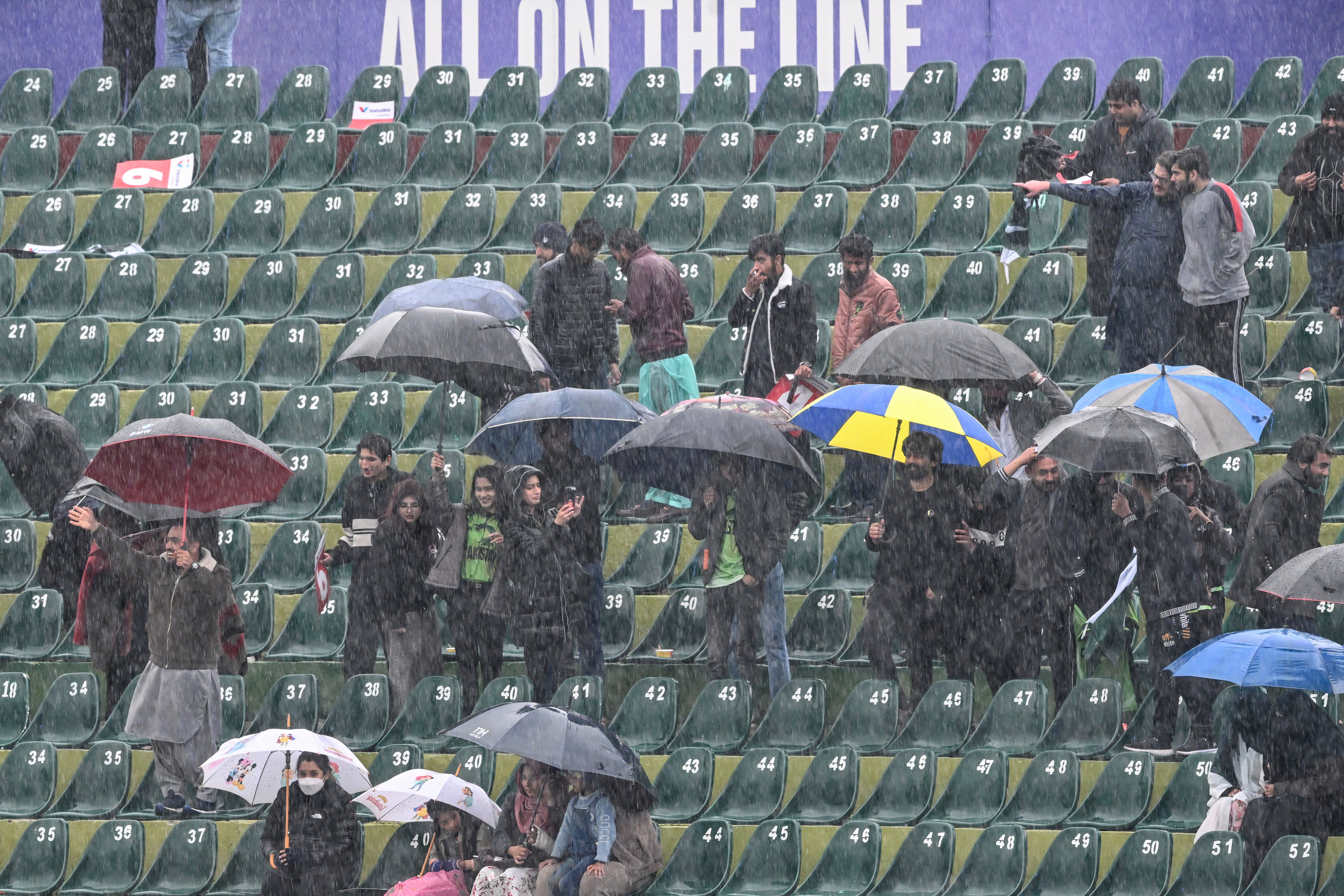 Spectators wait as rain delays the start of the ICC Champions Trophy one-day international (ODI) cricket match between Pakistan and Bangladesh at the Rawalpindi Cricket Stadium in Rawalpindi on February 27, 2025. Pakistan's last Champions Trophy group match with Bangladesh on February 27, was abandoned without a ball being bowled in Rawalpindi because of rain, ensuring the host country's title defence ended with a wet whimper. Pakistan's failure to advance beyond the group phase or even win a game was a huge letdown for a country hosting its first major tournament in three decades. (Photo by Farooq NAEEM / AFP)