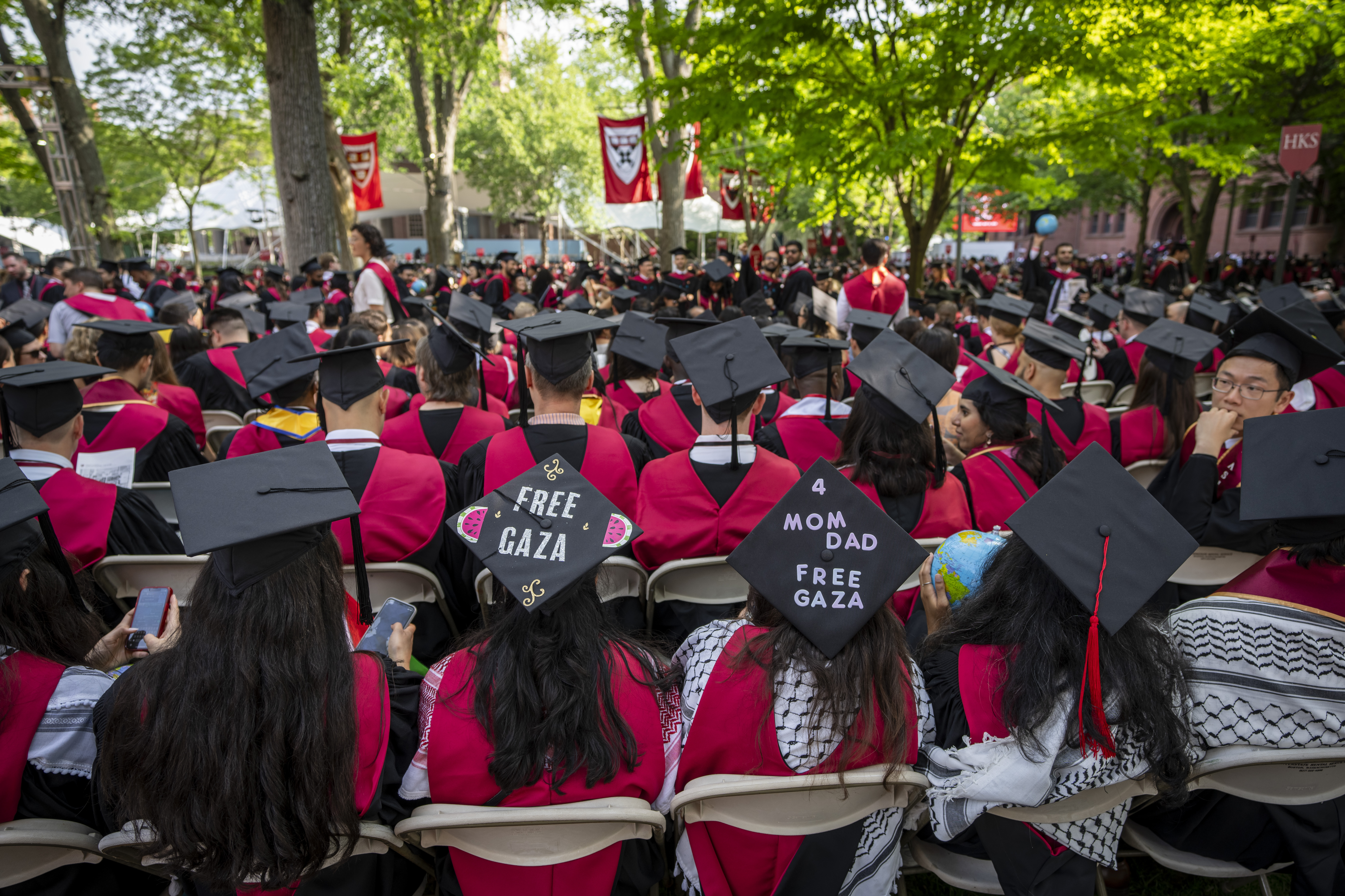 Students wear signs supporting Palestinians in Gaza on their mortarboards during commencement in Harvard Yard