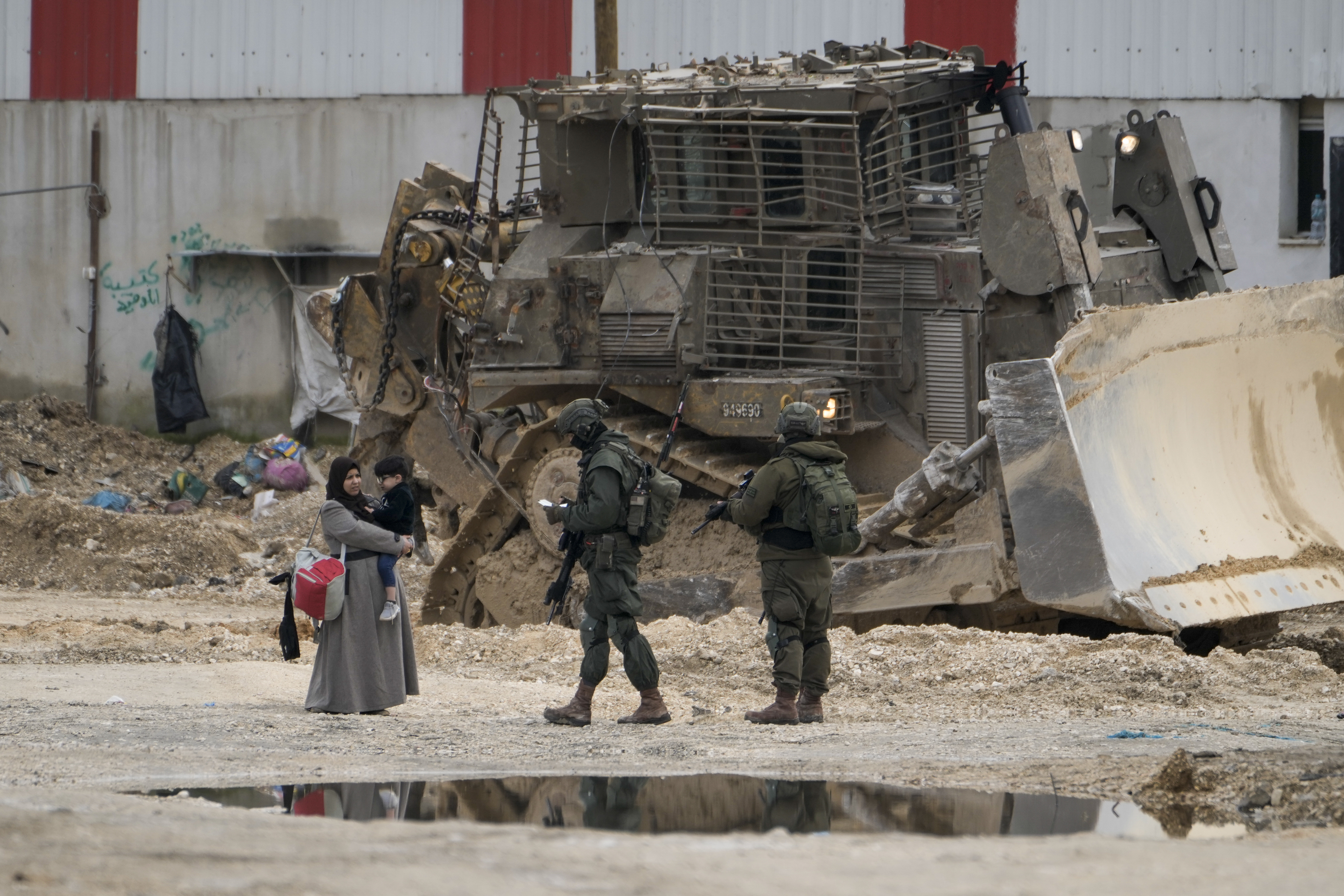 Israeli soldiers check the ID of Palestinians in the West Bank refugee camp of Nur Shams