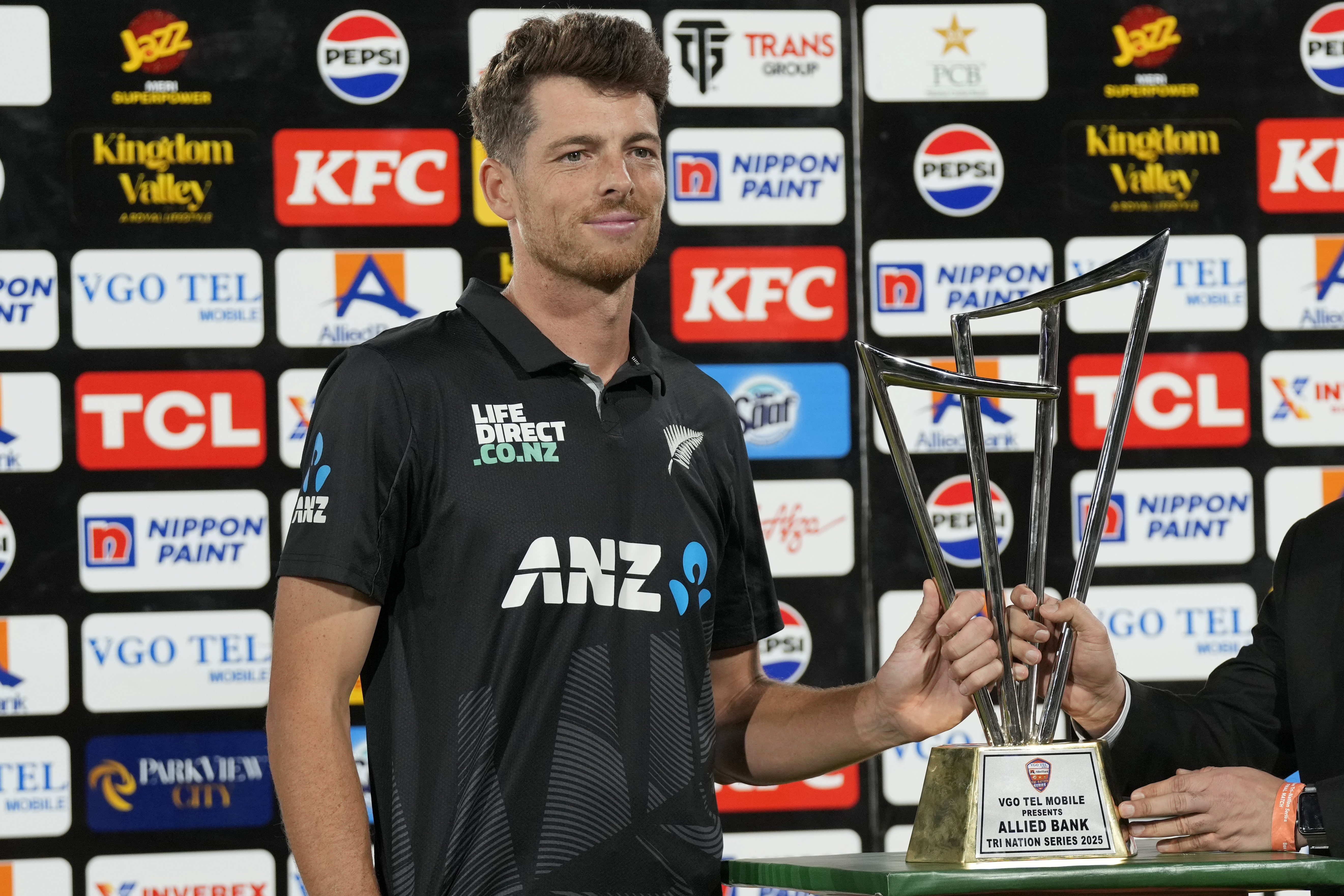 New Zealand's skipper Mitchel Santner receives trophy after winning the tri-series final against Pakistan, in Karachi, Pakistan, Friday, Feb. 14, 2025. (AP Photo/Fareed Khan)