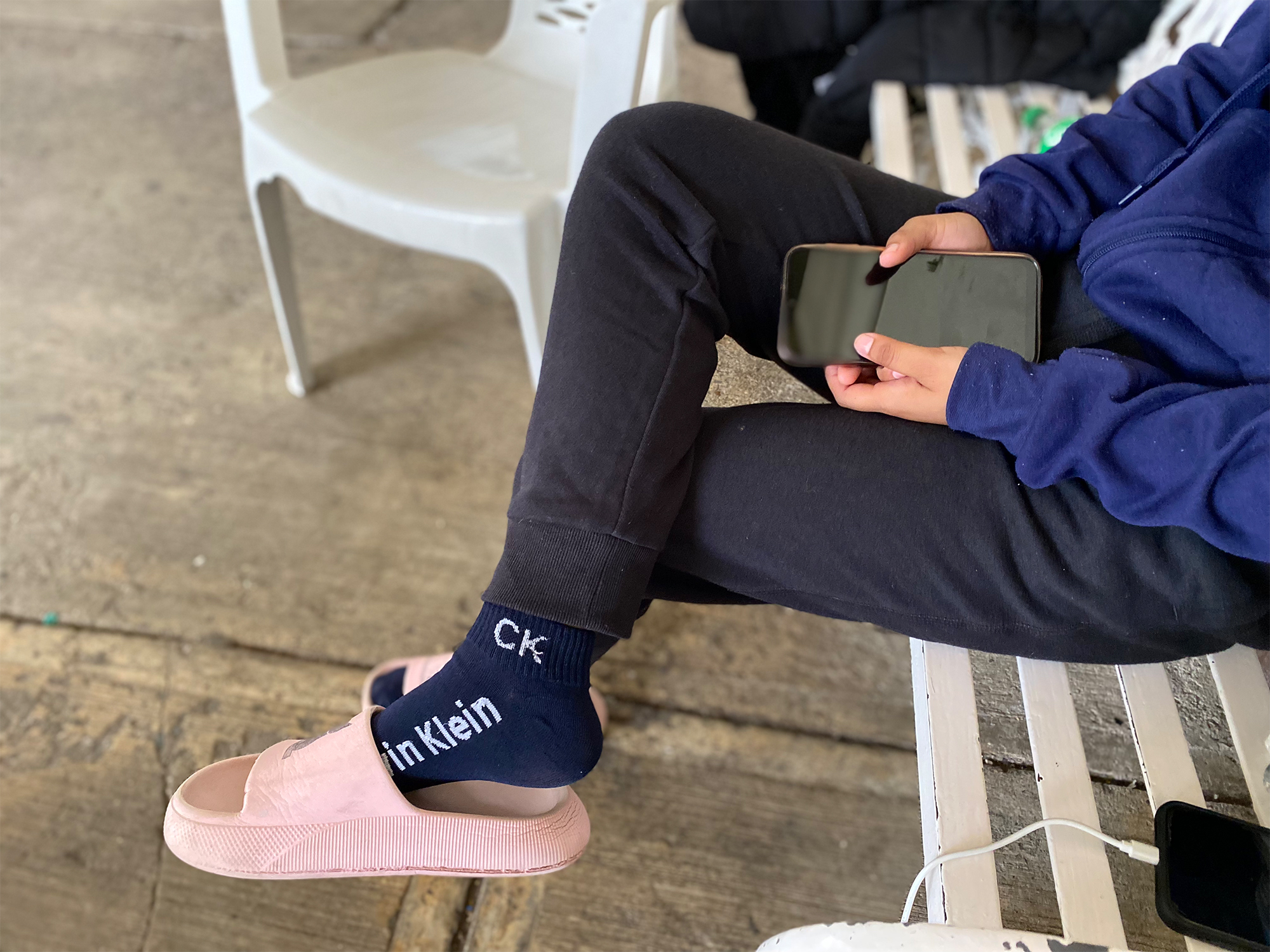 A migrant sits cross-legged with a phone