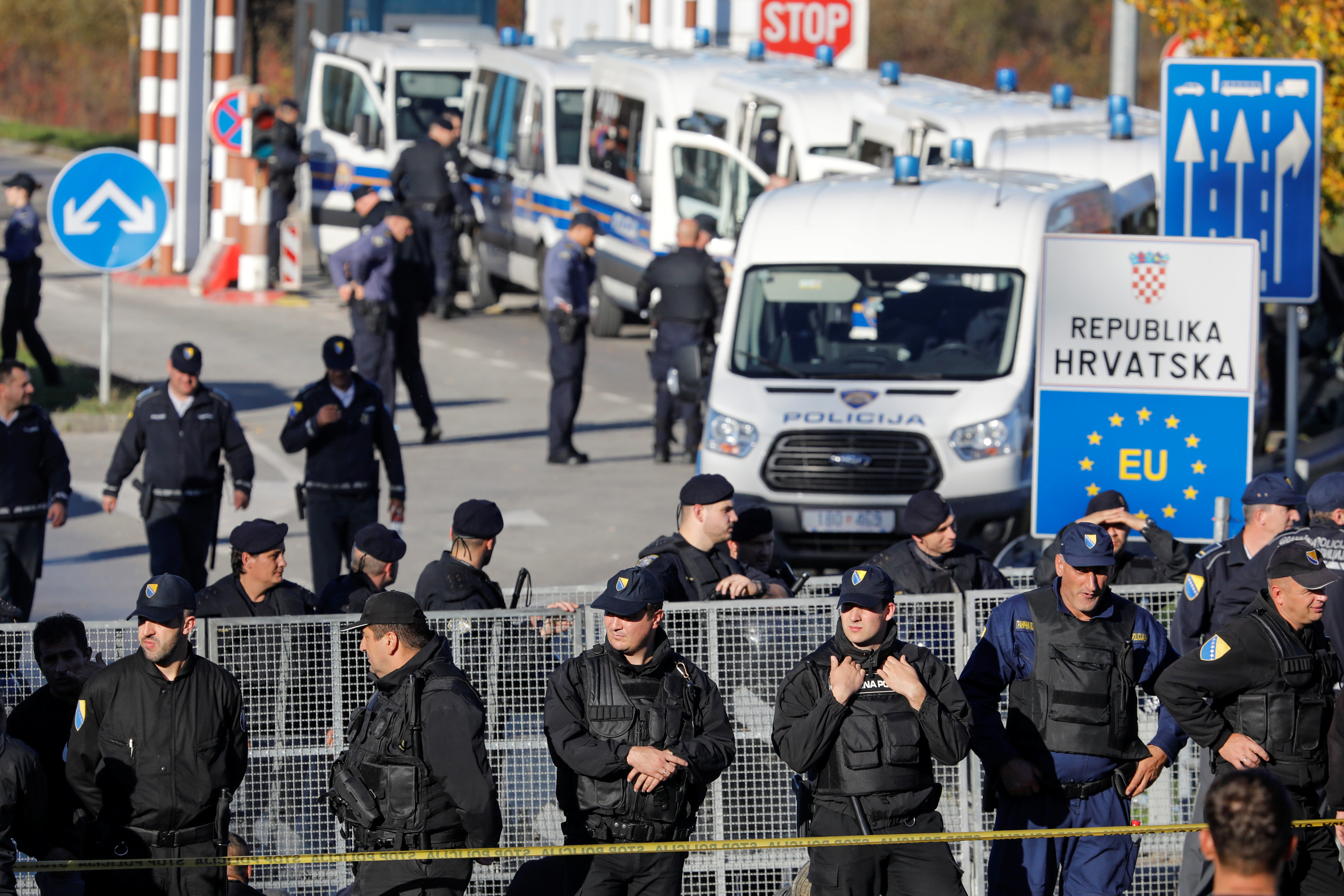 Bosnian and Croatian border police stand guard in front of migrants at Maljevac border crossing between Bosnia and Croatia near Velika Kladusa, Bosnia, October 24, 2018. REUTERS/Marko Djurica