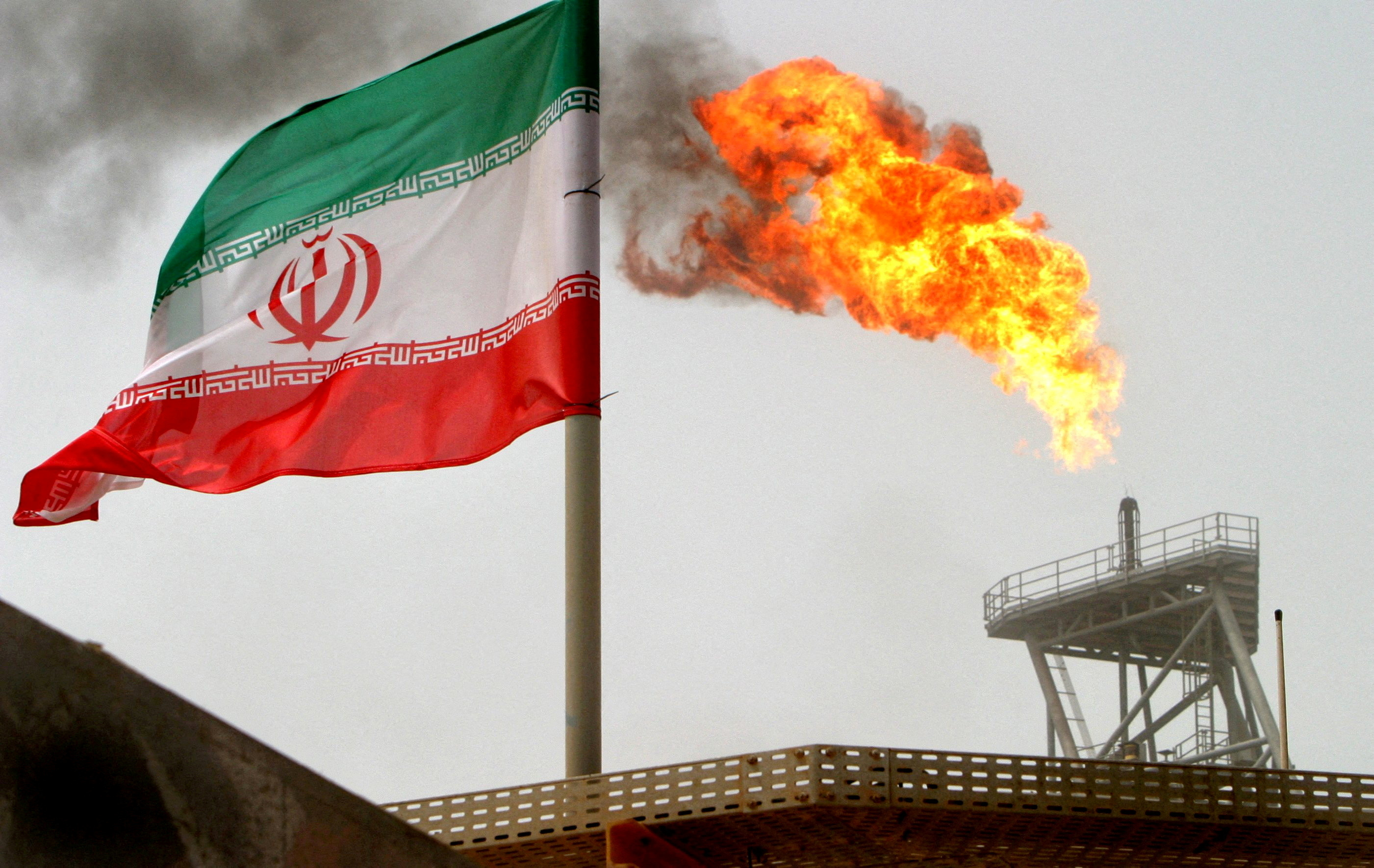 FILE PHOTO: A gas flare on an oil production platform is seen alongside an Iranian flag in the Gulf July 25, 2005. REUTERS/Raheb Homavandi/File Photo