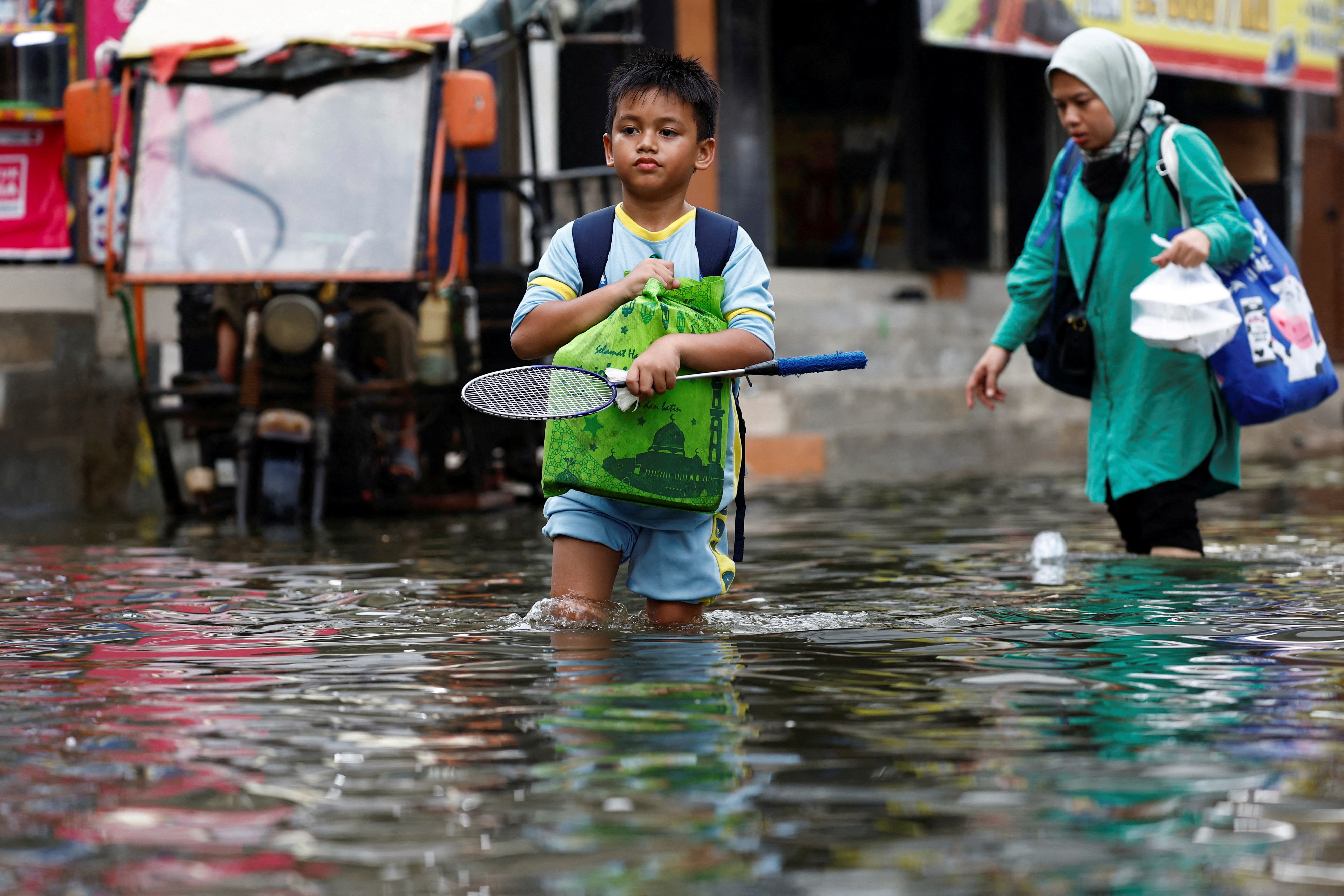 FILE PHOTO: People walk through water at a flooded area affected by rising sea levels and land subsidence in North Jakarta, Indonesia, November 20, 2024. REUTERS/Willy Kurniawan/File Photo