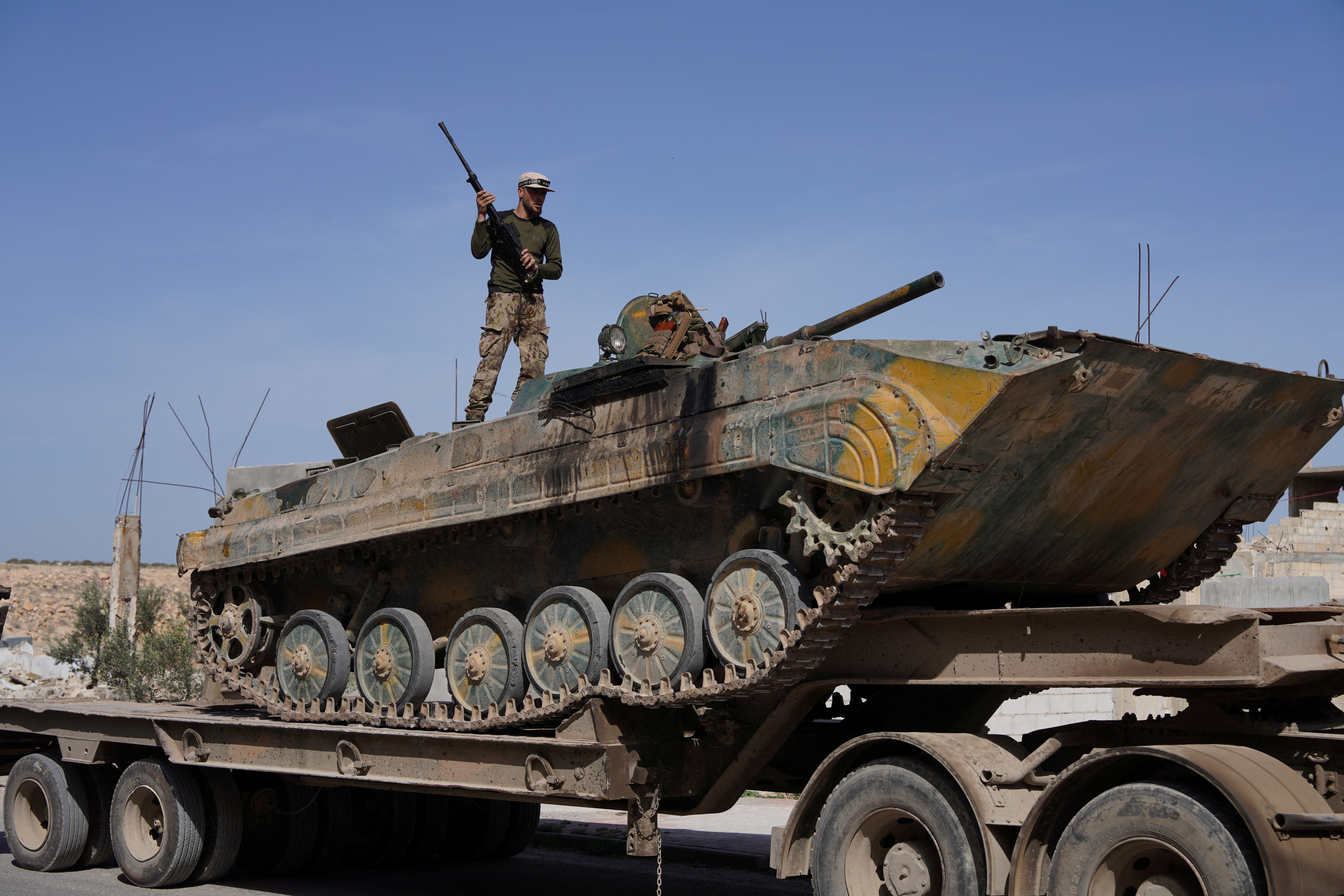 Syrian troops ride atop a towed military vehicle as they head towards the Syrian-Lebanese border following clashes with Lebanese soldiers and armed groups, in Qusayr, Syria, March 17, 2025. REUTERS/Karam al-Masri