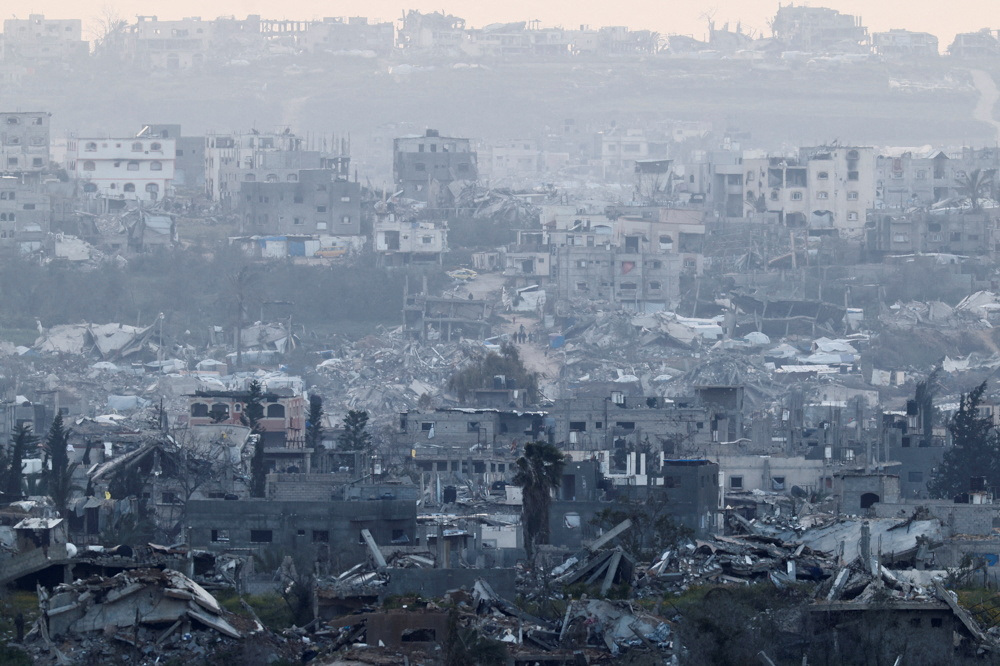 People walk among destroyed buildings in Gaza, as viewed from the Israel-Gaza separation fence, March 20, 2025 [Amir Cohen/Reuters]