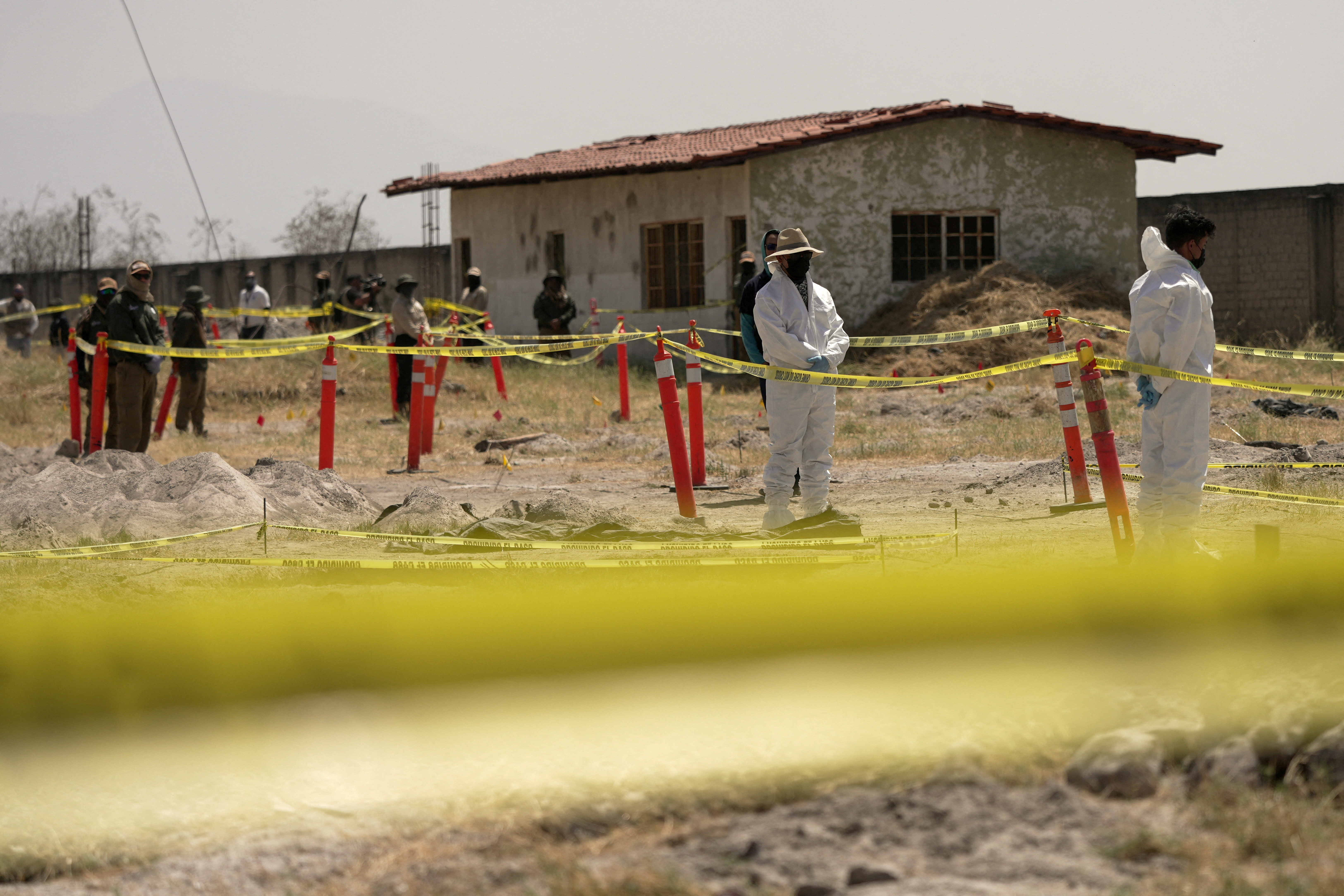 Forensic experts examine a site at the Izaguirre Ranch, behind yellow caution tape.