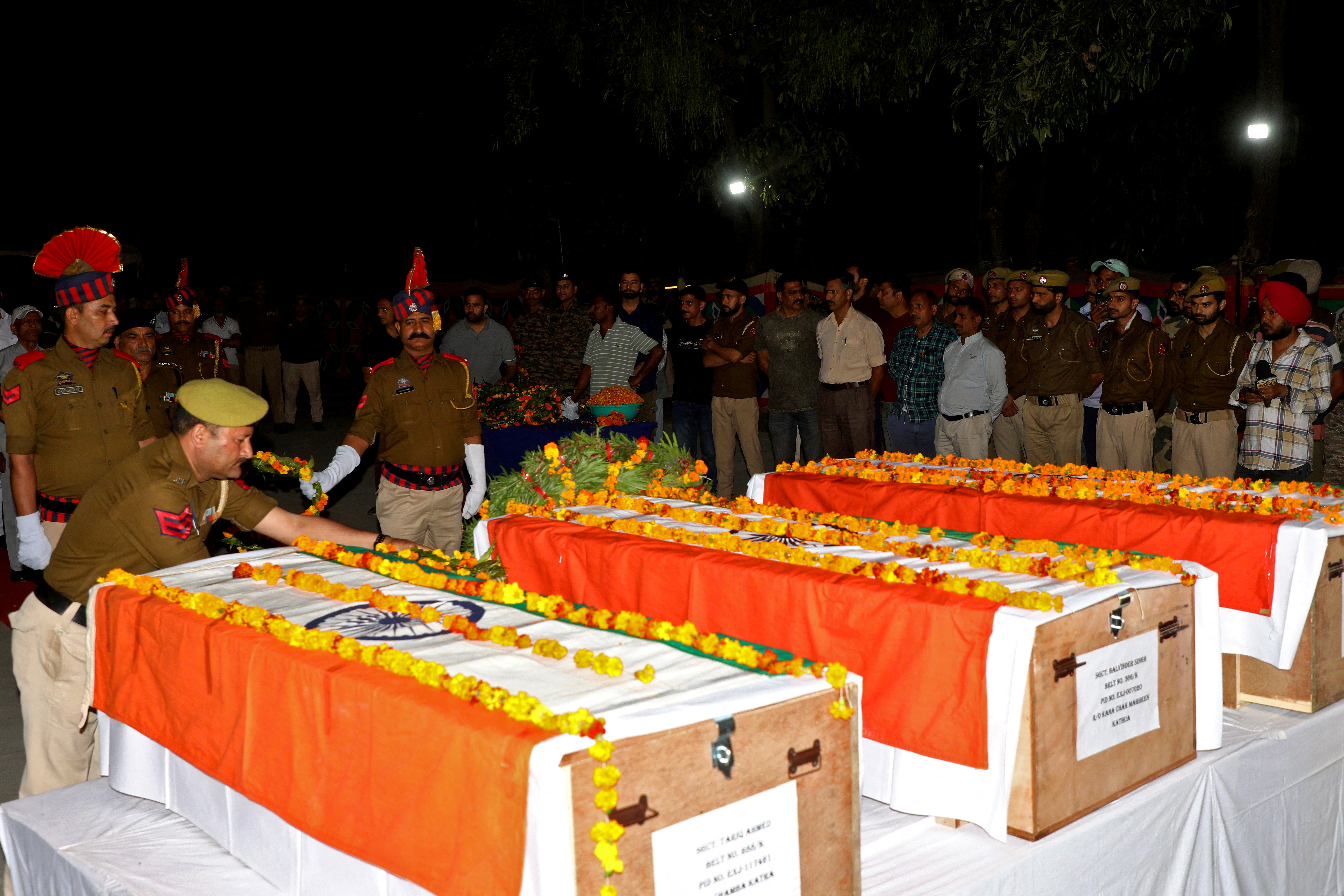 Police officers place wreaths on the coffins containing the bodies of their colleagues