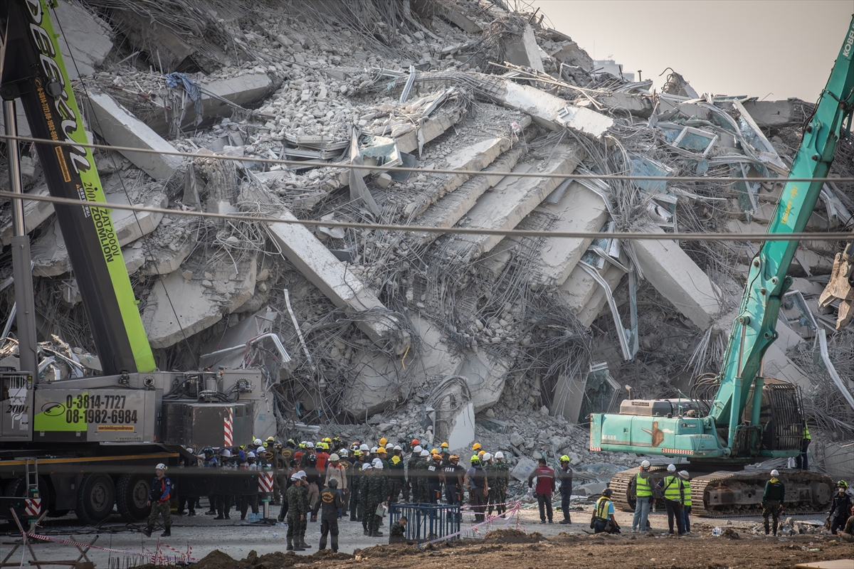 people stand next to a collapsed building