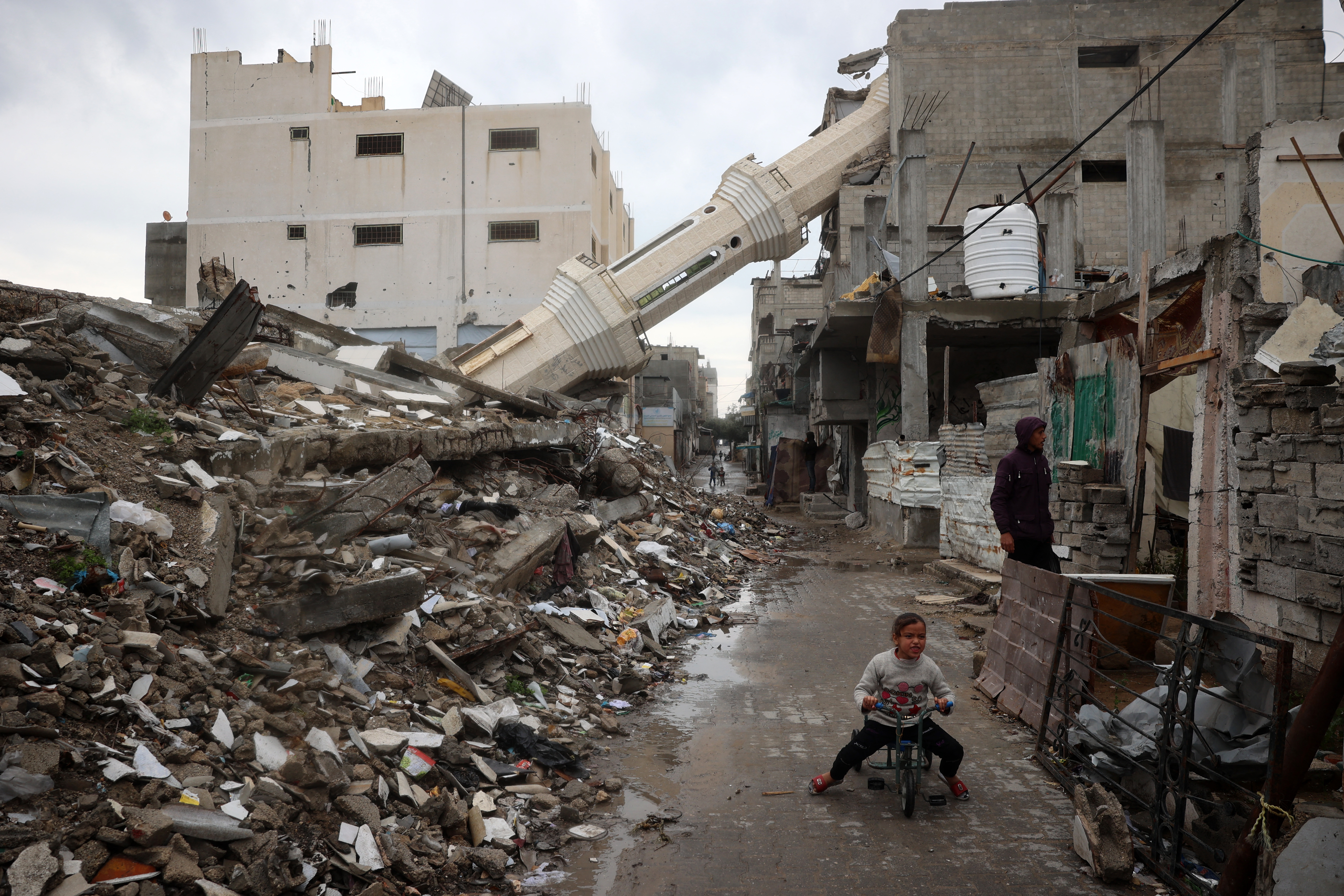 A Palestinian child rides a bicycle near a fallen minaret [File: Eyad Baba/AFP]