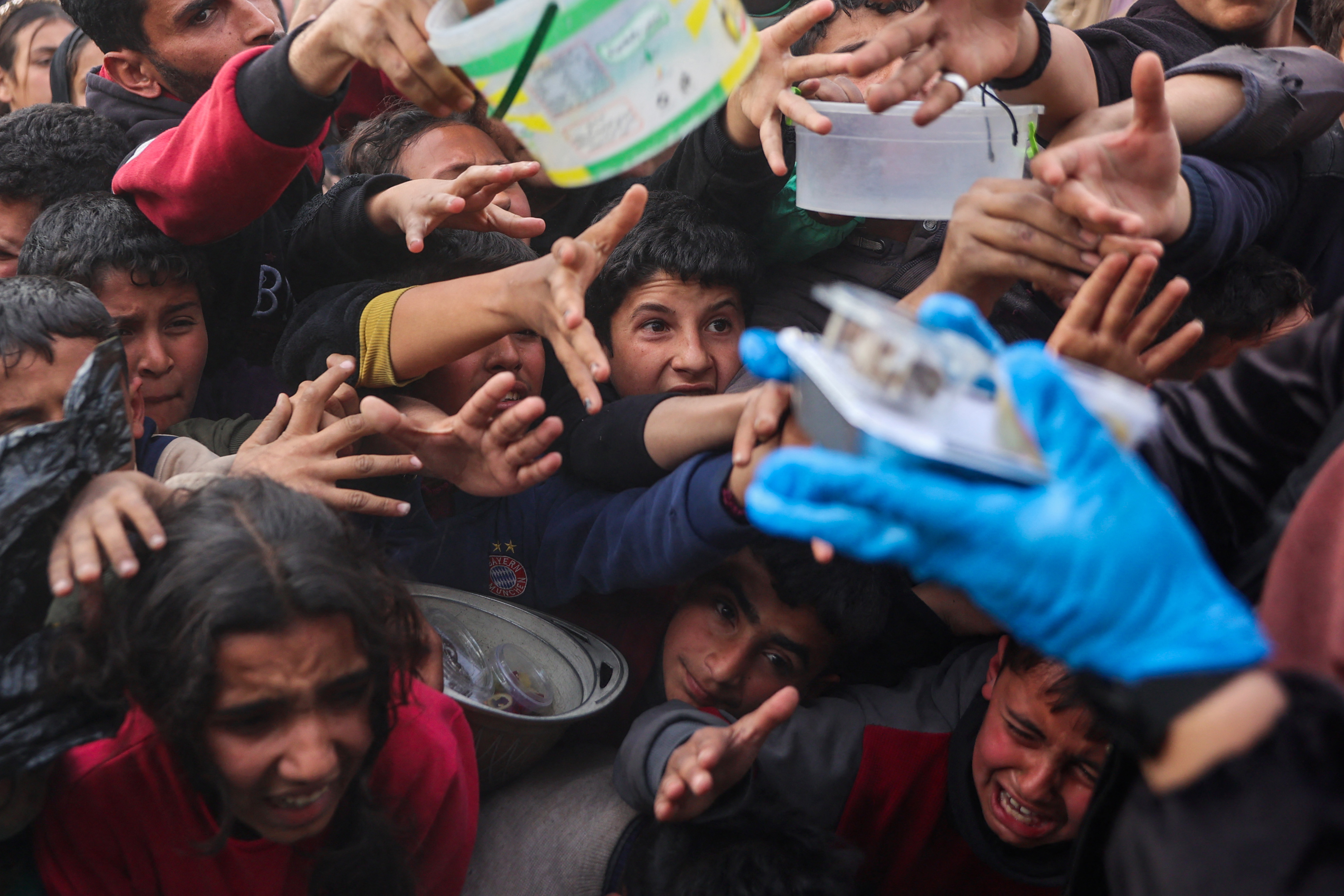 Displaced Palestinian children push into a queue to get a portion of cooked food from a charity kitchen in Beit Lahia in the northern Gaza Strip, ahead of the iftar fast-breaking meal during the Muslim holy month of Ramadan on March 9, 2025.