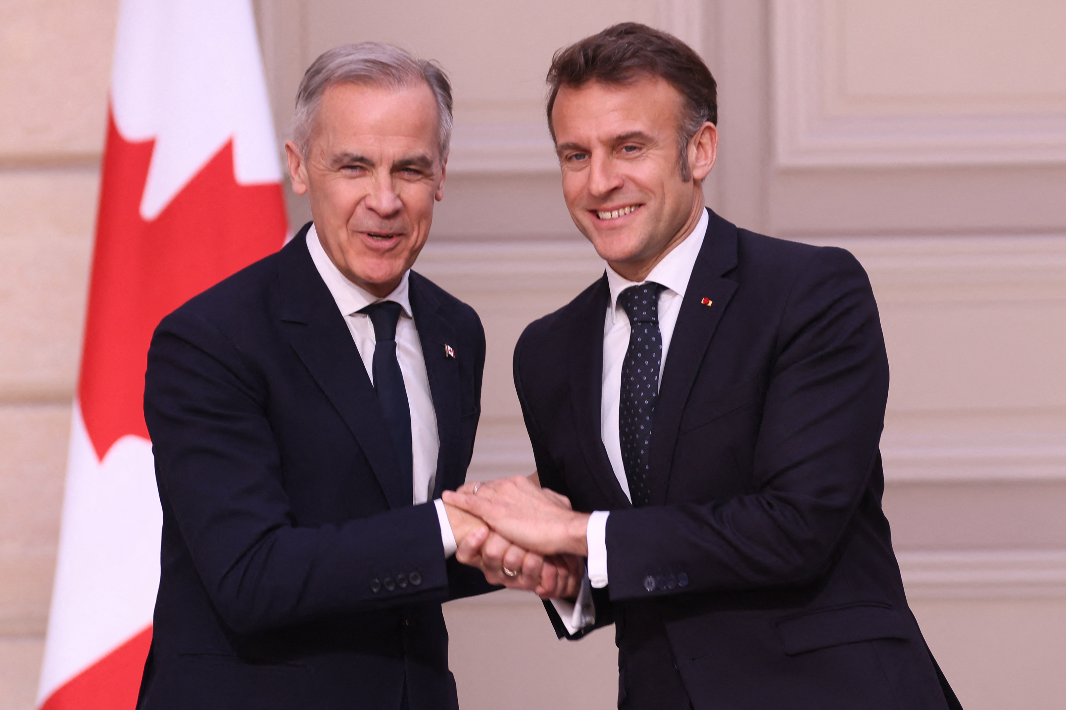 France's President Emmanuel Macron (R) and Canada's newly appointed Prime Minister Mark Carney (L) shake hands
