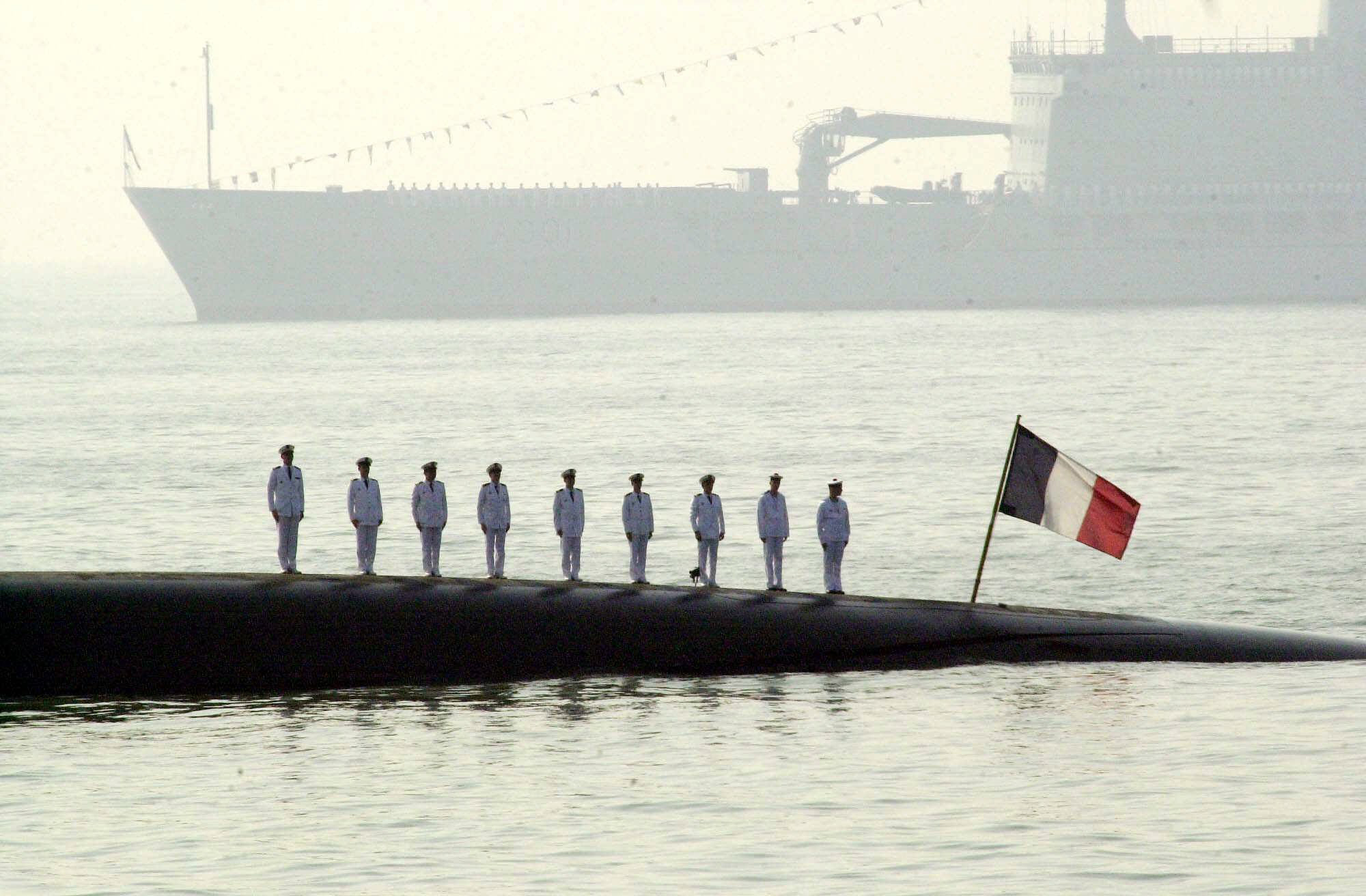 FILE - In this Feb.17, 2001 file photo, French naval officers on board the French nuclear submarine Perle stand at attention during India's first International Fleet Review, off Bombay's coast. Firefighters battled a blaze on the Perle that broke out Friday June 12, 2020 during renovation work. The submarine's nuclear reactor, nuclear fuel and weapons were removed five months ago to prepare for the renovations, so not at risk from the blaze, according to an official with the regional maritime authority. (AP Photo/Sherwin Crasto, File)