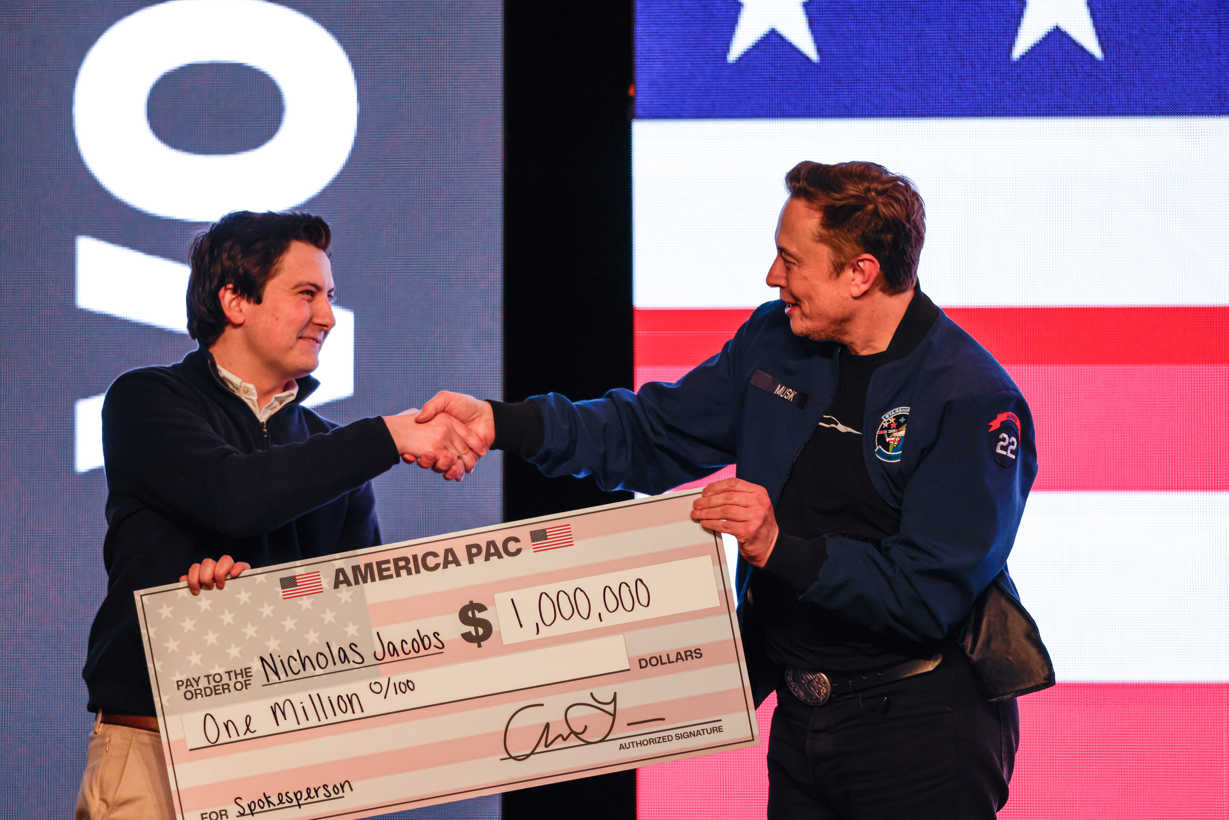 Elon Musk presents a cheque for 1 million dollars to a man during a town hall.