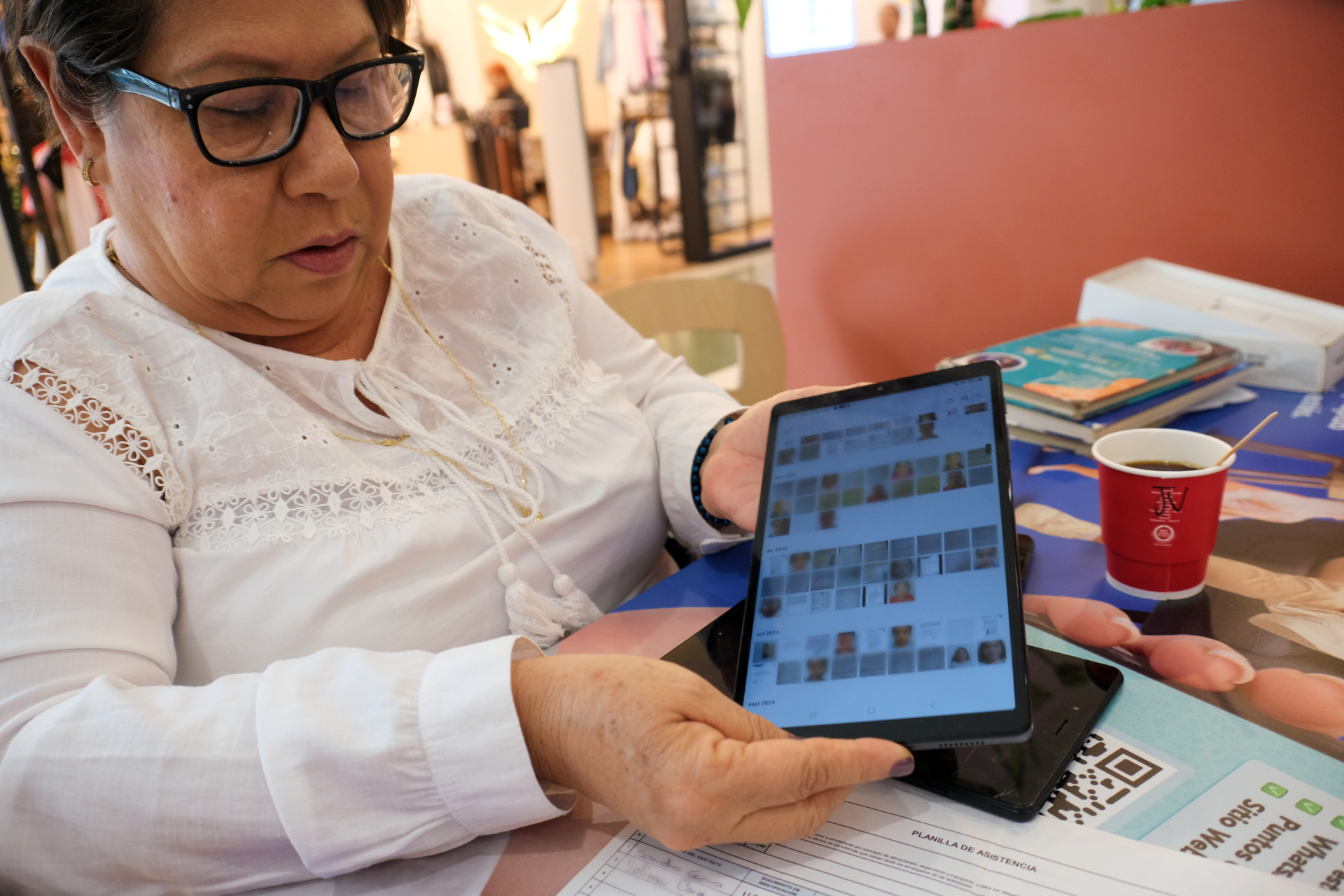Adriana Llano Medina lifts a tablet computer to show off documents for immigration registration