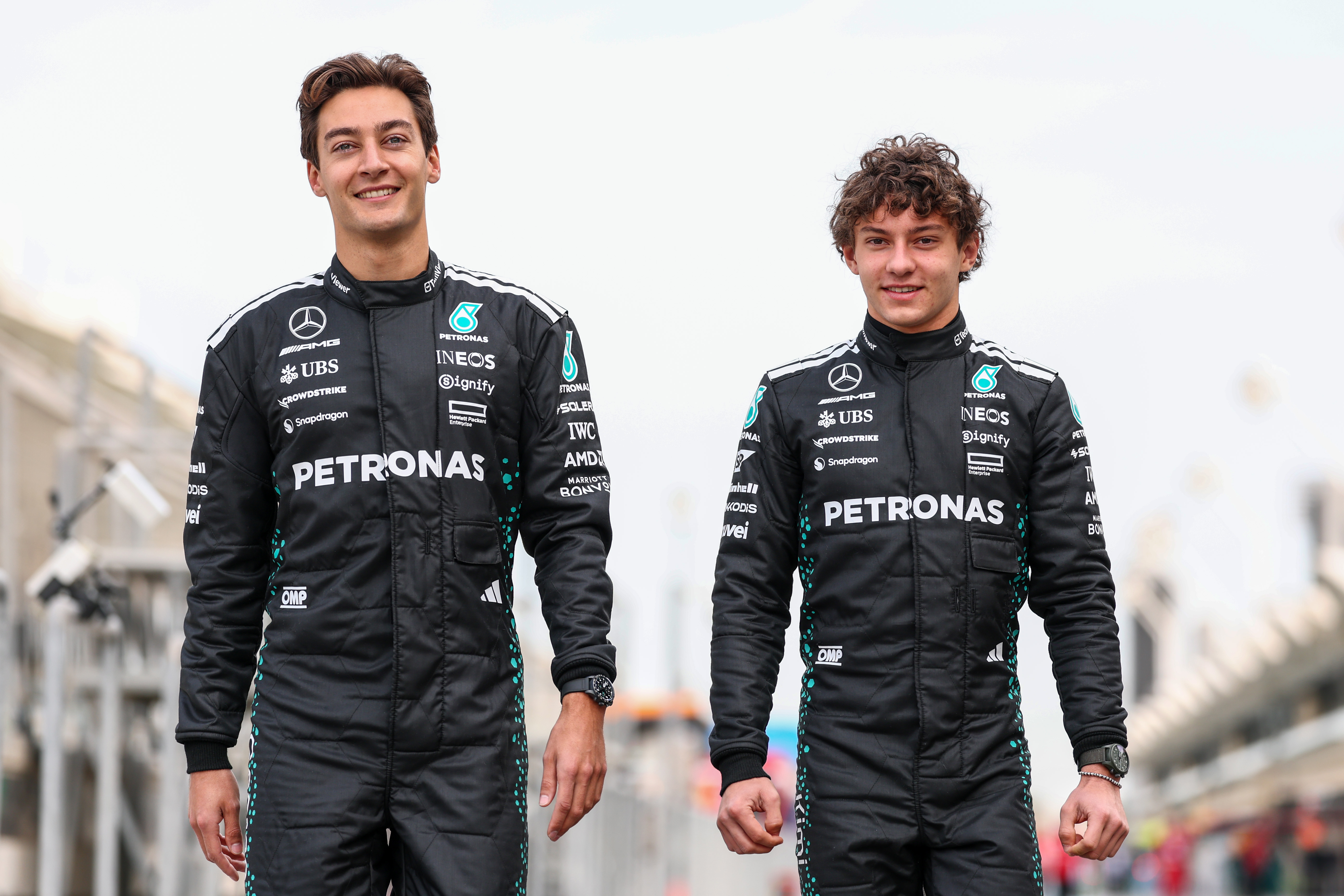 George Russell and Kimi Antonelli walking next to track.